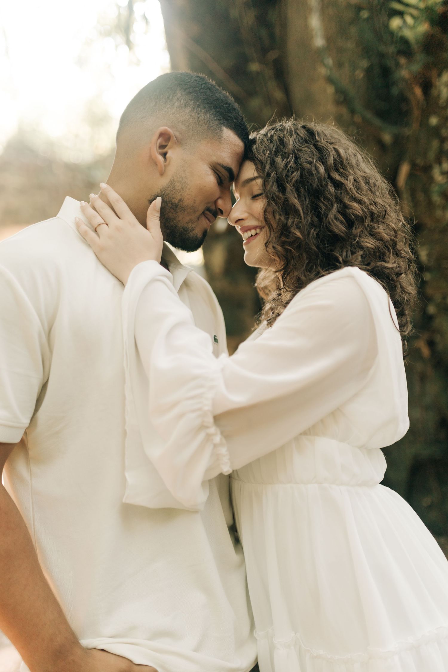 Romantic couple's photoshoot featuring tender embraces in forest setting with soft lighting.