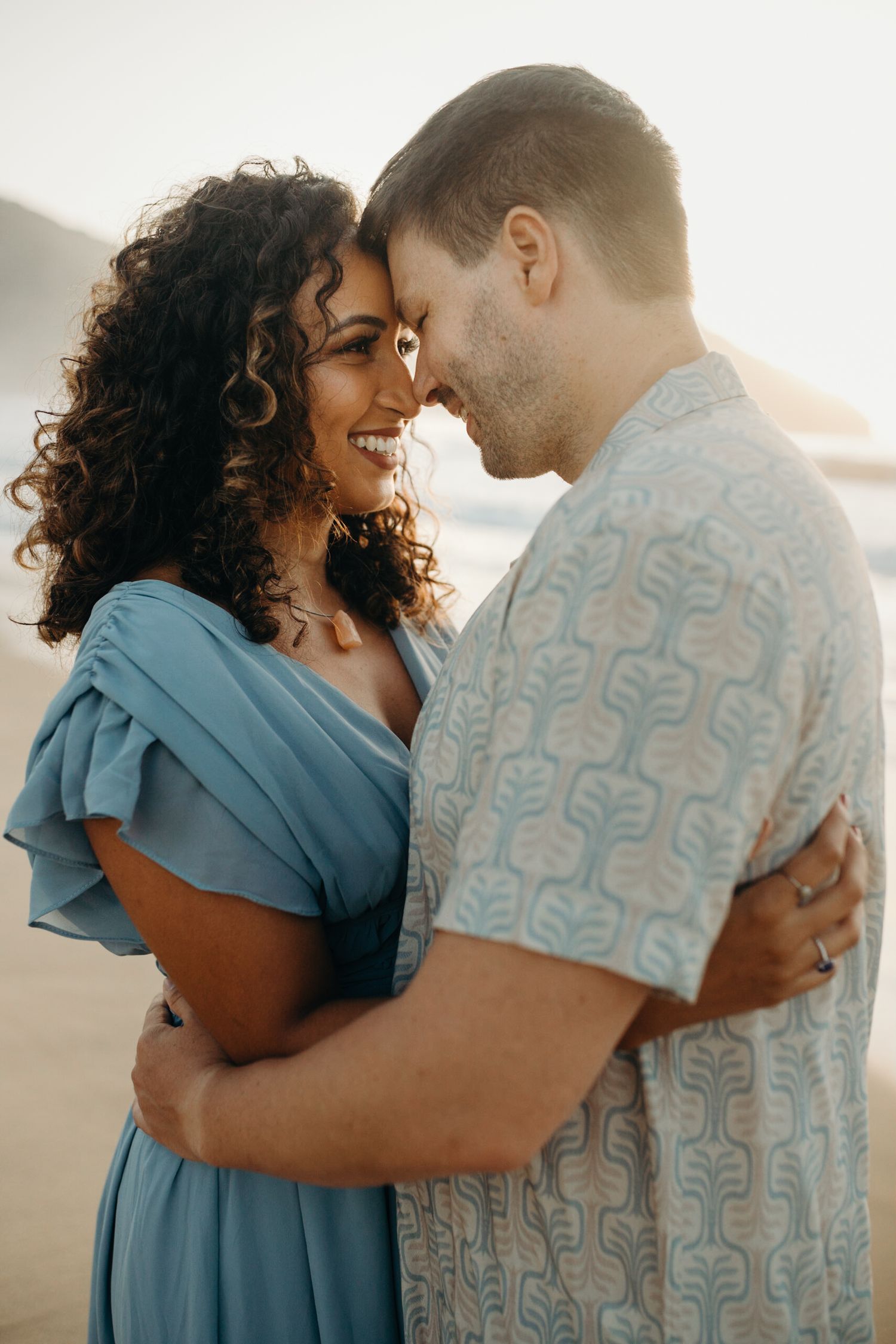 Romantic couple sharing intimate moment on beach during golden hour.