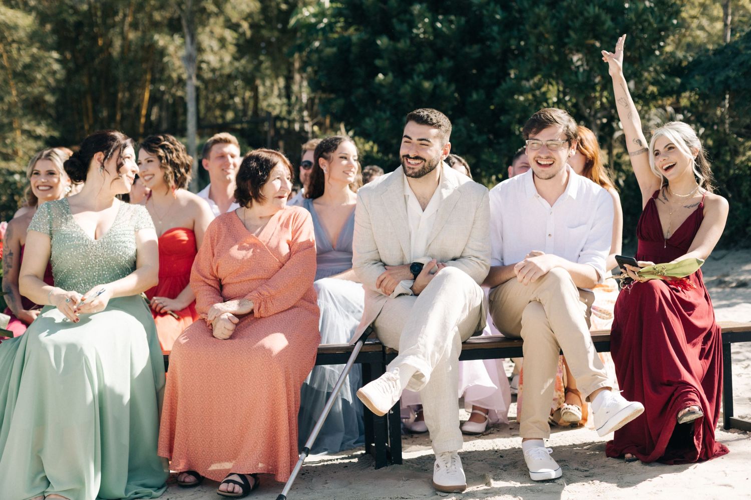 Wedding guests seated in colorful attire at an outdoor ceremony.