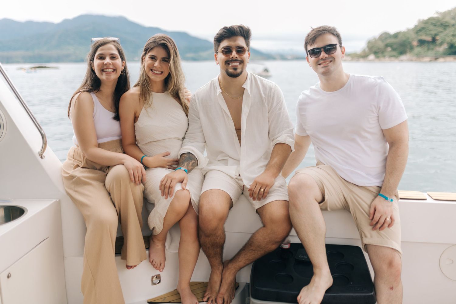Casual group photo of friends sitting together on boat deck with coastal scenery.