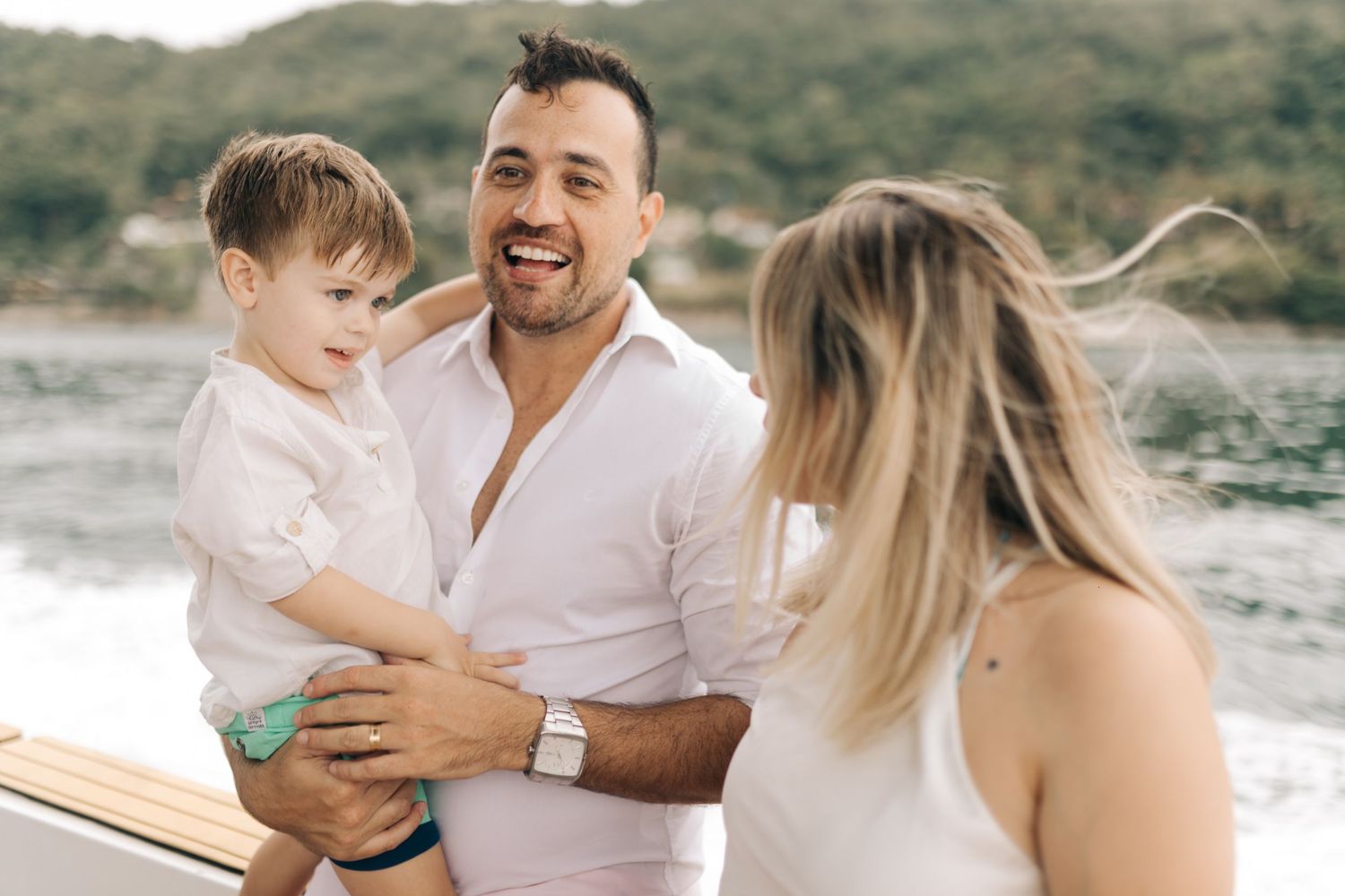 Family sharing a moment together on boat deck with coastal scenery.