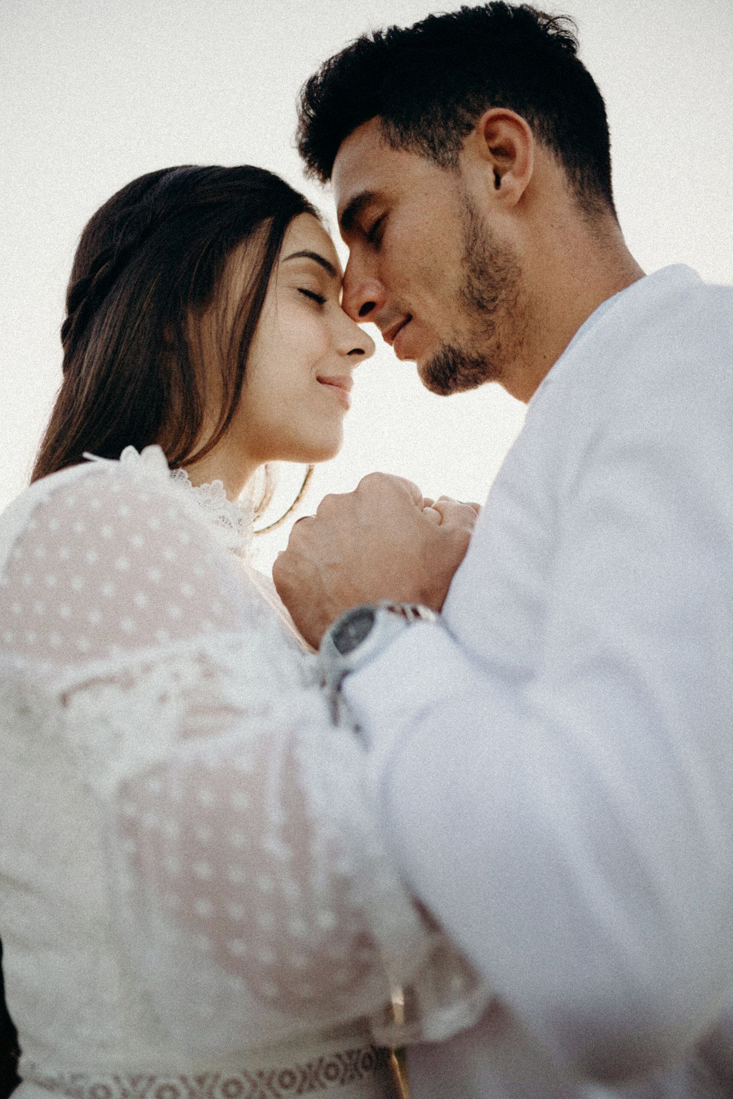 Monochrome series of tender moments between couple in white clothing.