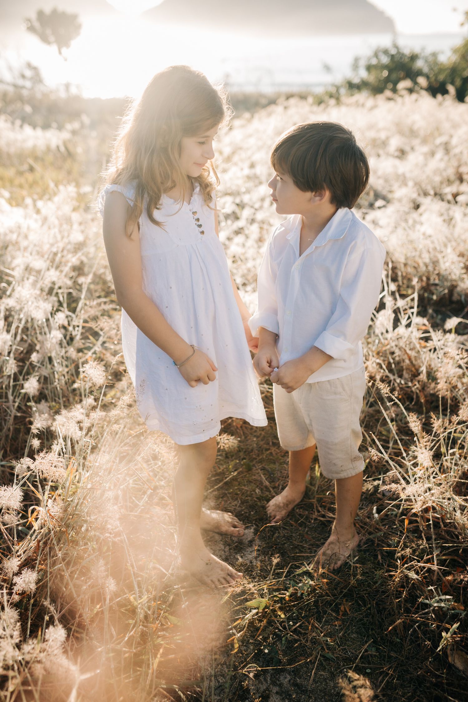 Kids interact playfully among tall grasses during a sunny outdoor photoshoot.
