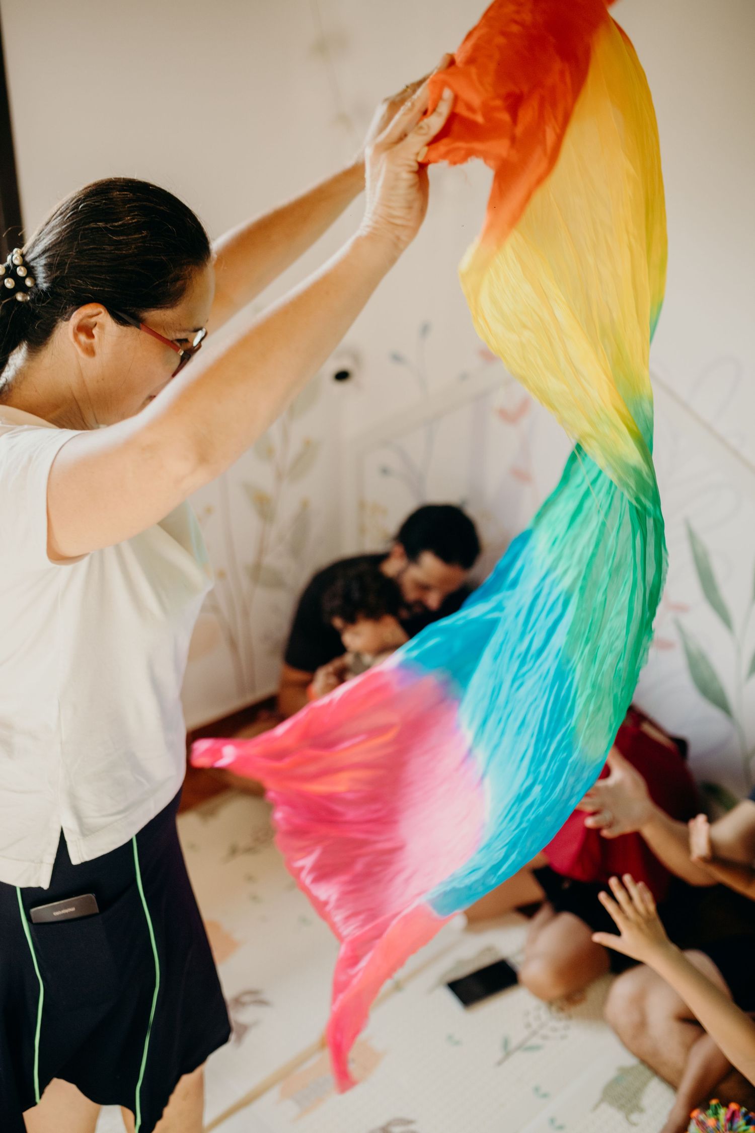 Colorful silk fabric being waved during a group activity session.