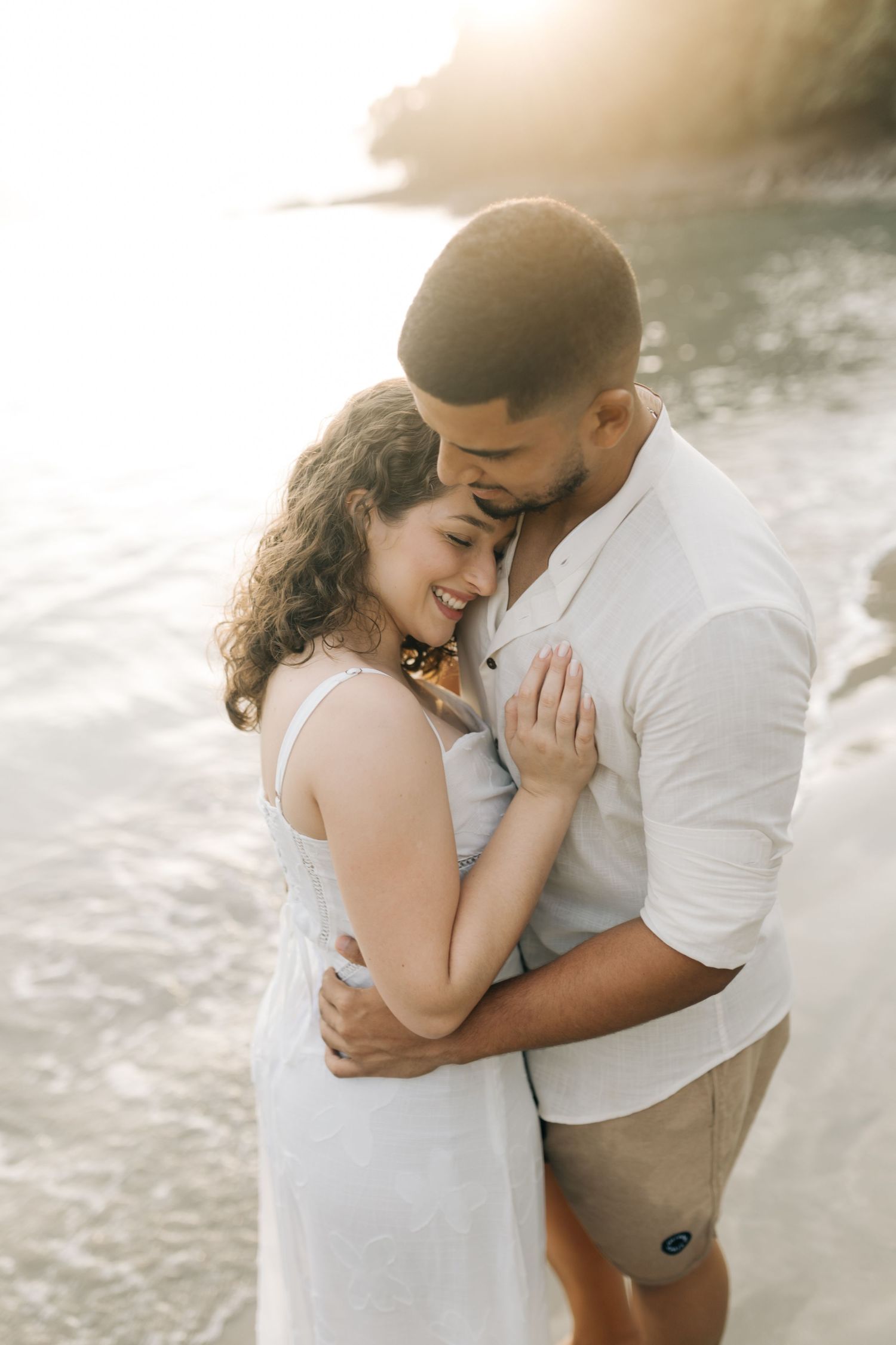 Romantic couple sharing an intimate moment on a beach during golden hour.