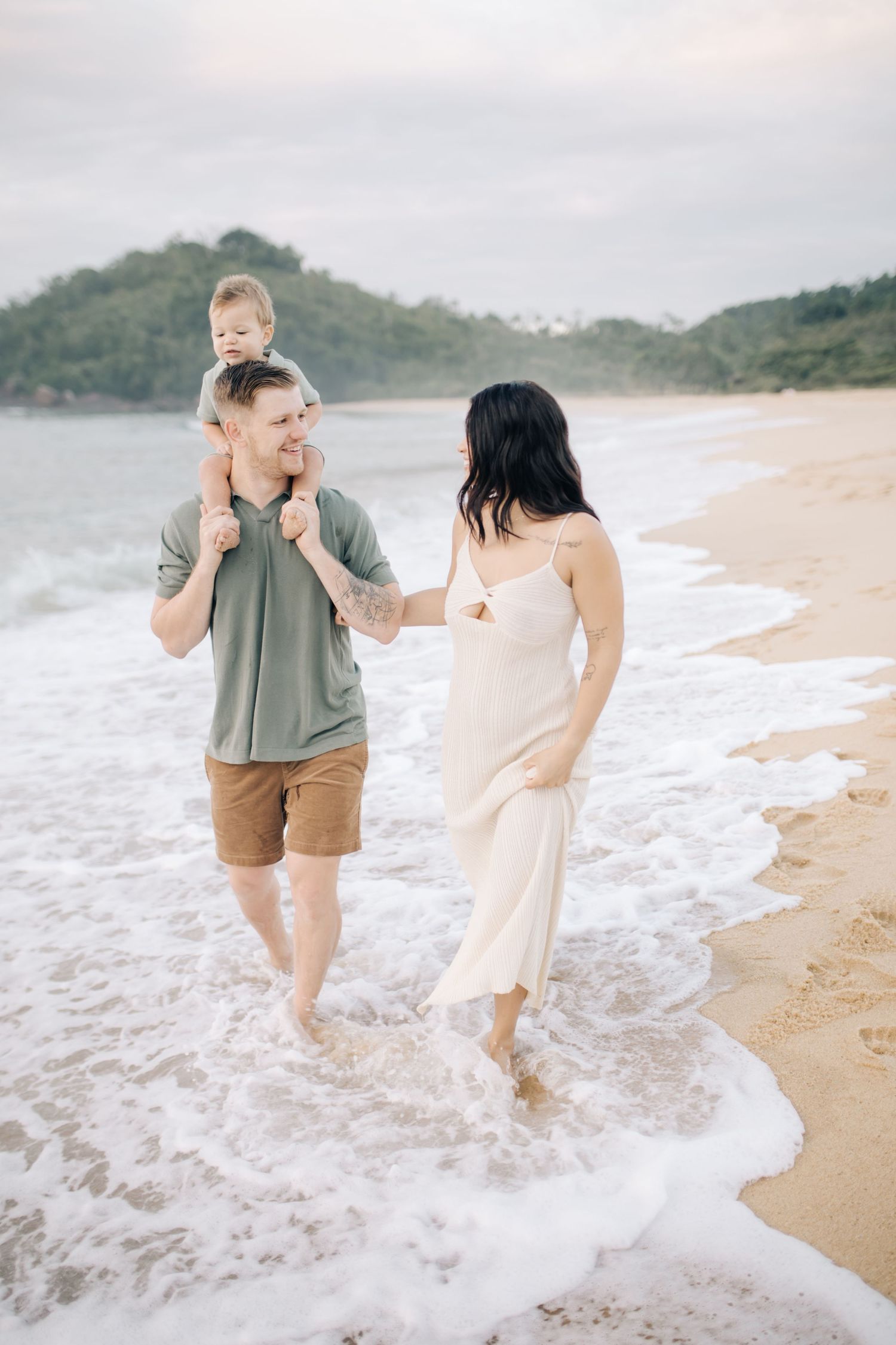 A couple plays in the ocean waves at a scenic beach, splashing water and enjoying a playful moment together.