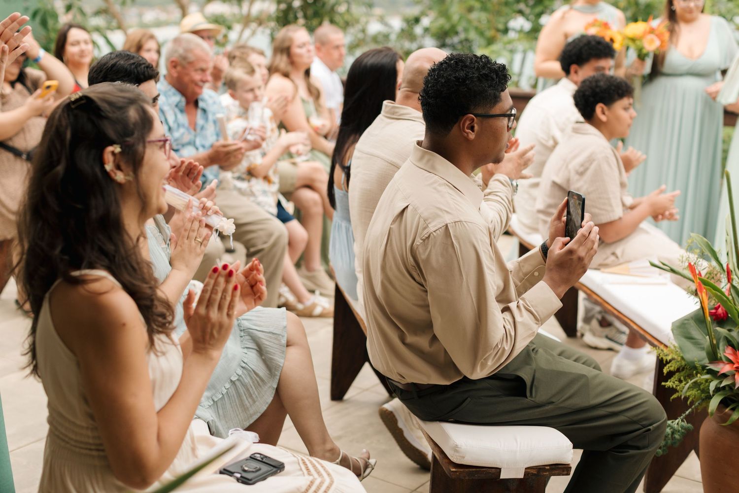 Wedding guests enjoying food and drinks at an outdoor reception with sunflowers and greenery.
