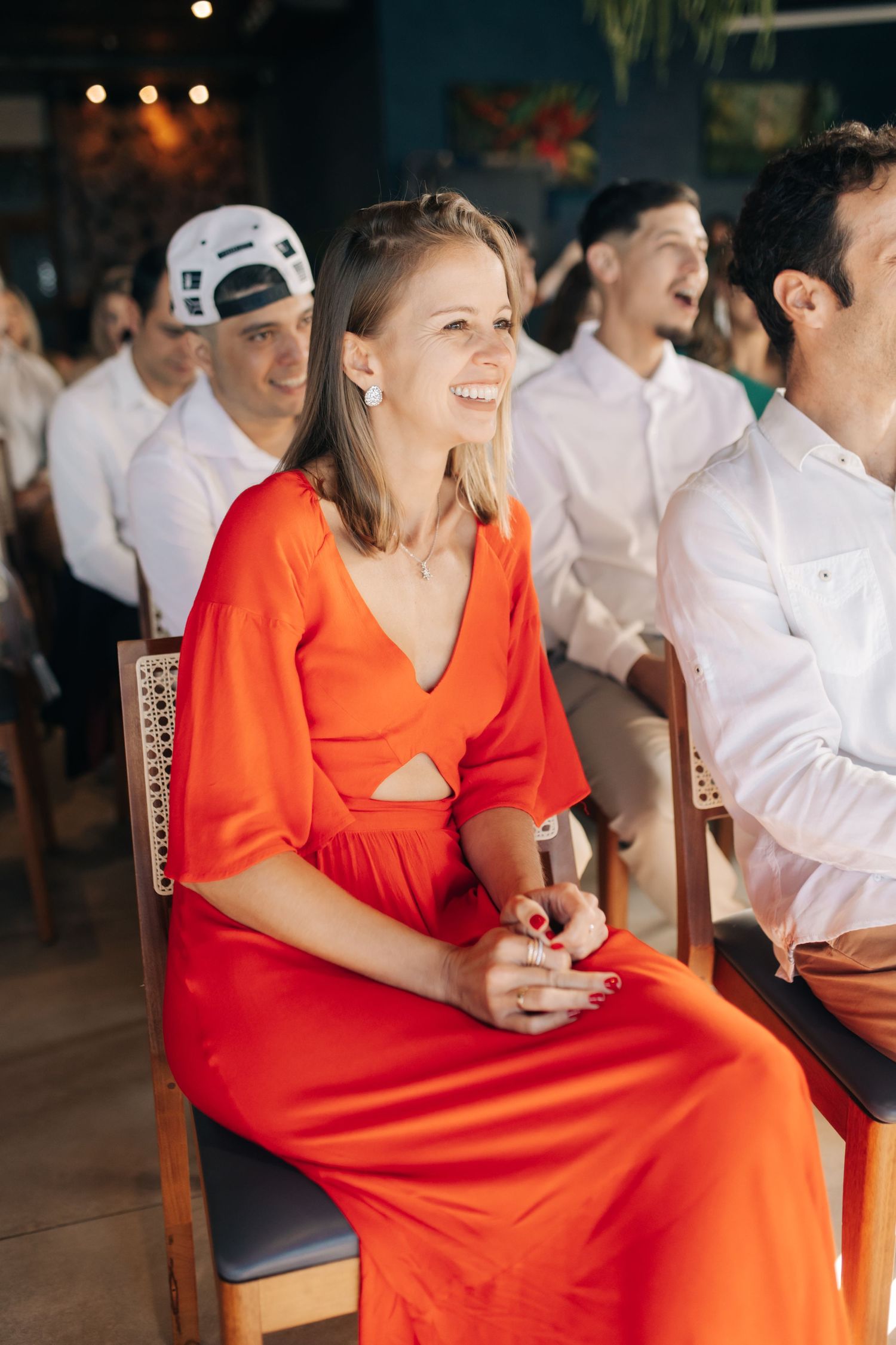 Guest in vibrant orange dress enjoying celebrations at wedding reception venue.
