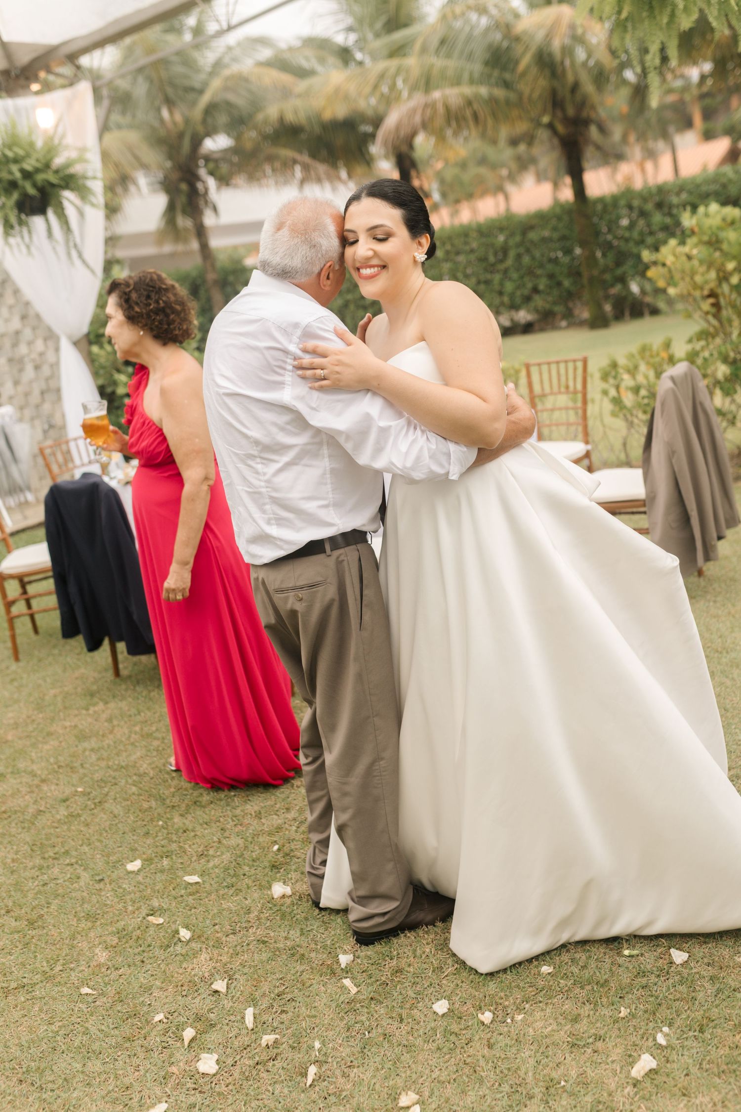 Wedding celebration on a lawn with guests in colorful attire and white decor.