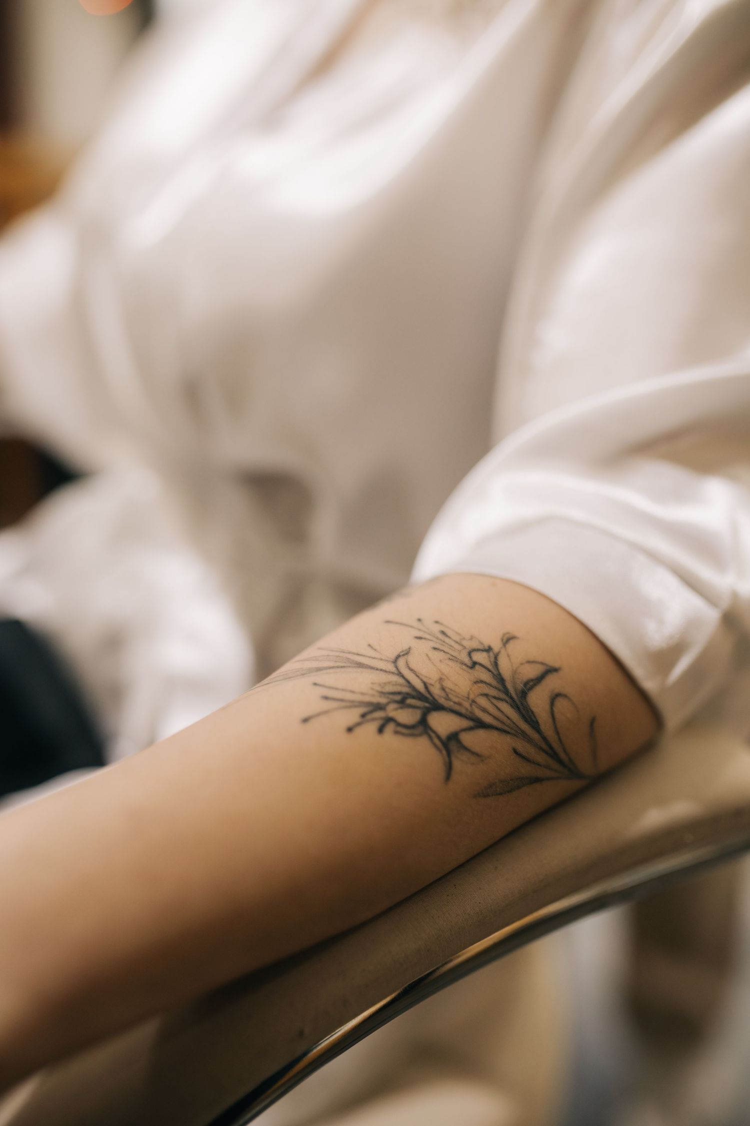 Delicate tree branch tattoo design shown on a person's forearm against a light background.