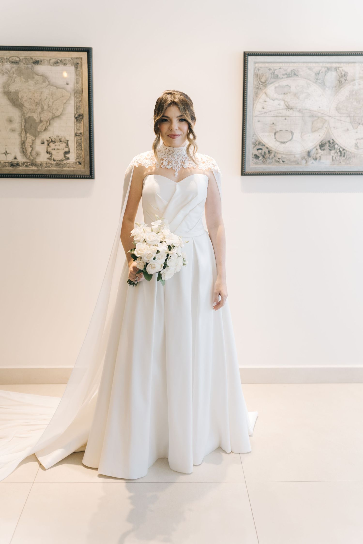 Elegant white wedding dress with sweetheart neckline and full skirt shown against wall with vintage map artwork.