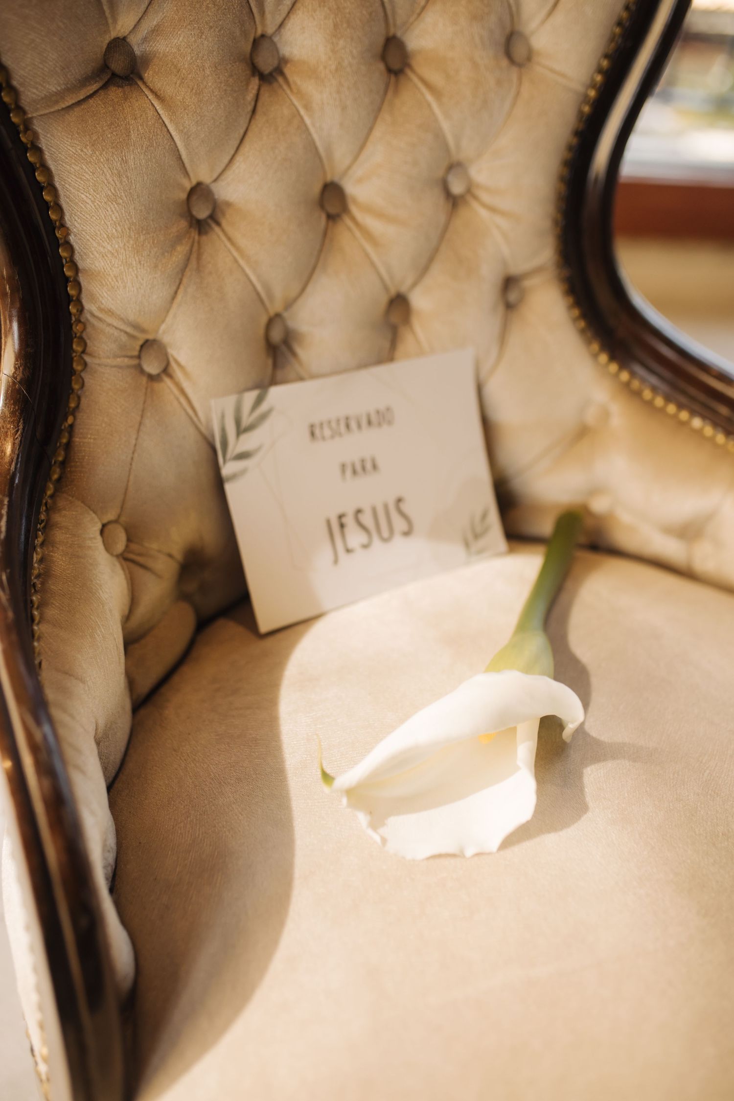 Elegant tufted beige chairs with name cards at formal event setting.