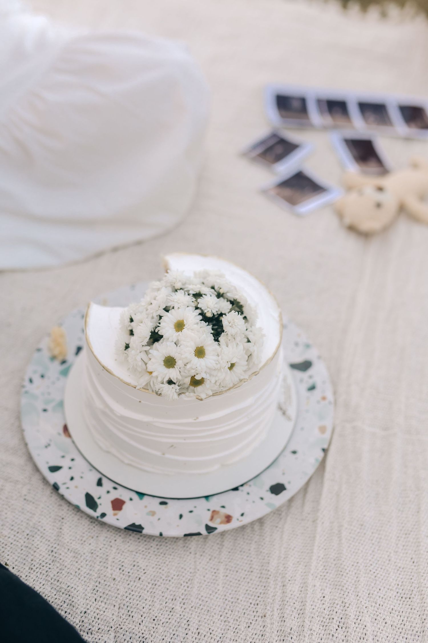 Small decorative white plates with delicate floral designs lay atop a textured beige linen tablecloth.