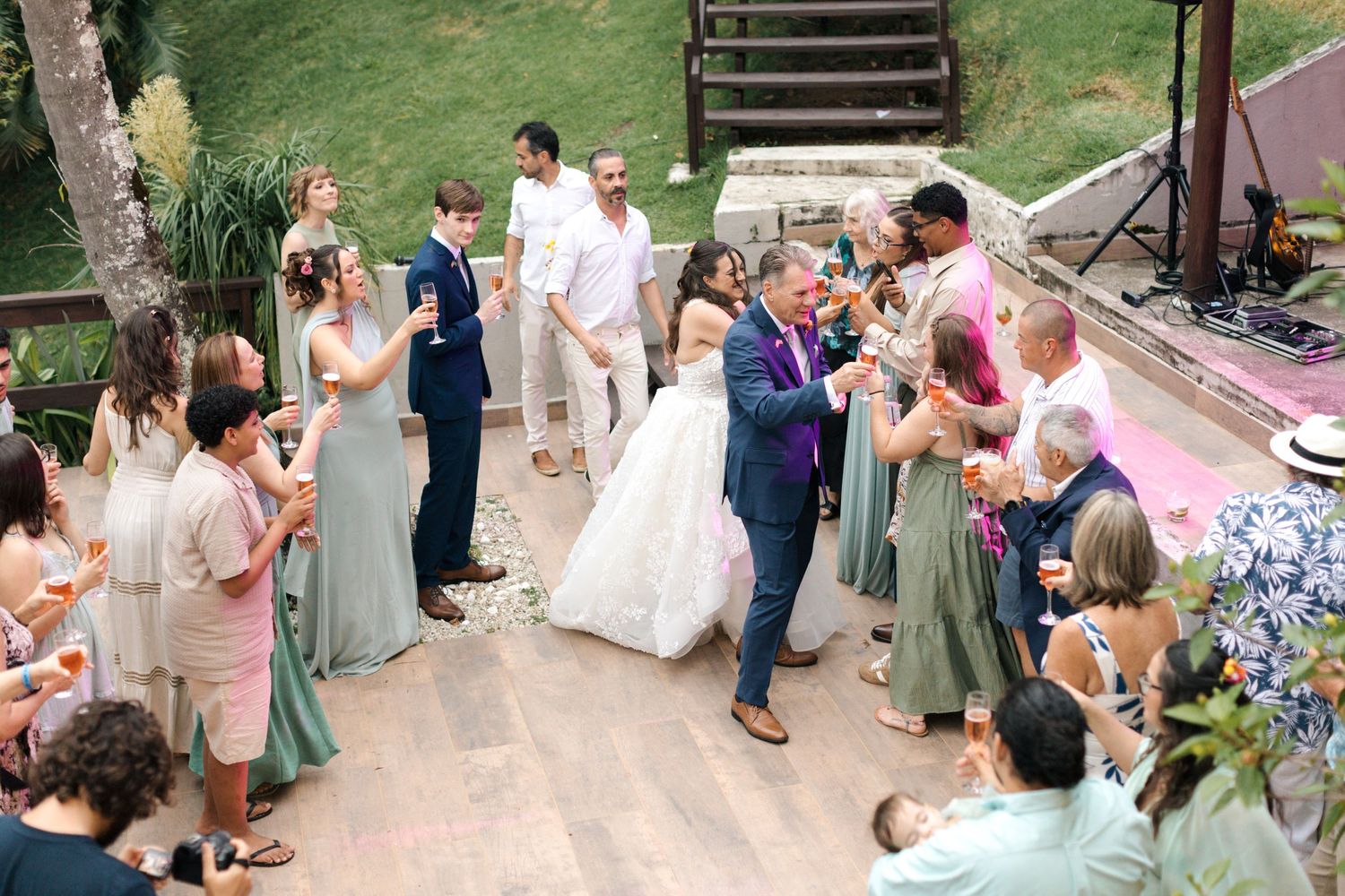 Wedding guests celebrate during an outdoor garden reception with string lights overhead.