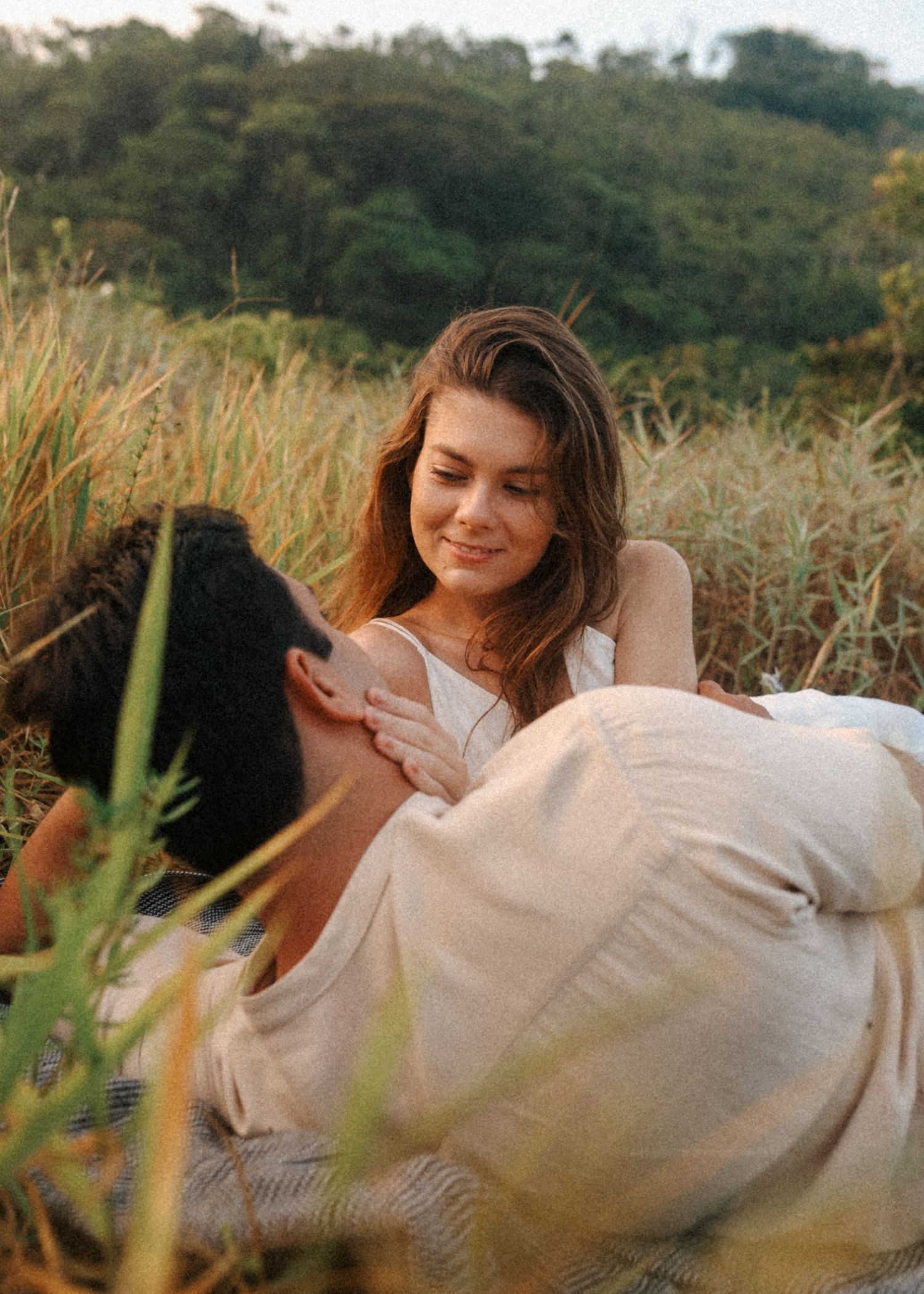 A romantic outdoor photoshoot in a field with mountains visible in the background.