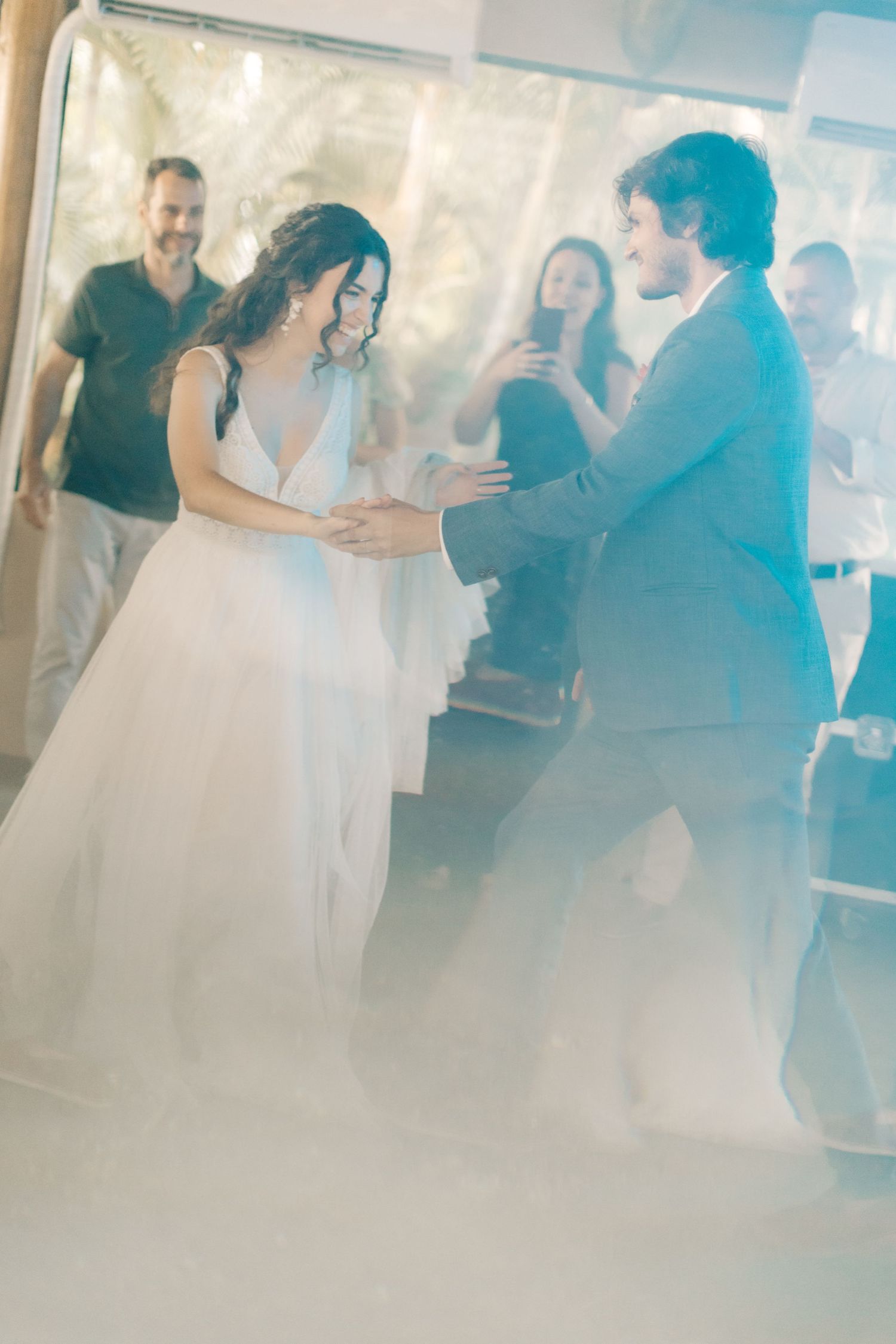 Dreamy blue-tinted photo captures dancing silhouettes at a wedding reception.