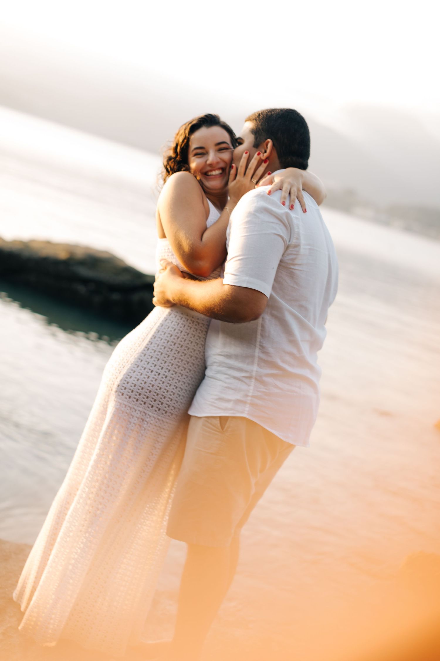 Joyful couple sharing an intimate moment during their beach photoshoot.