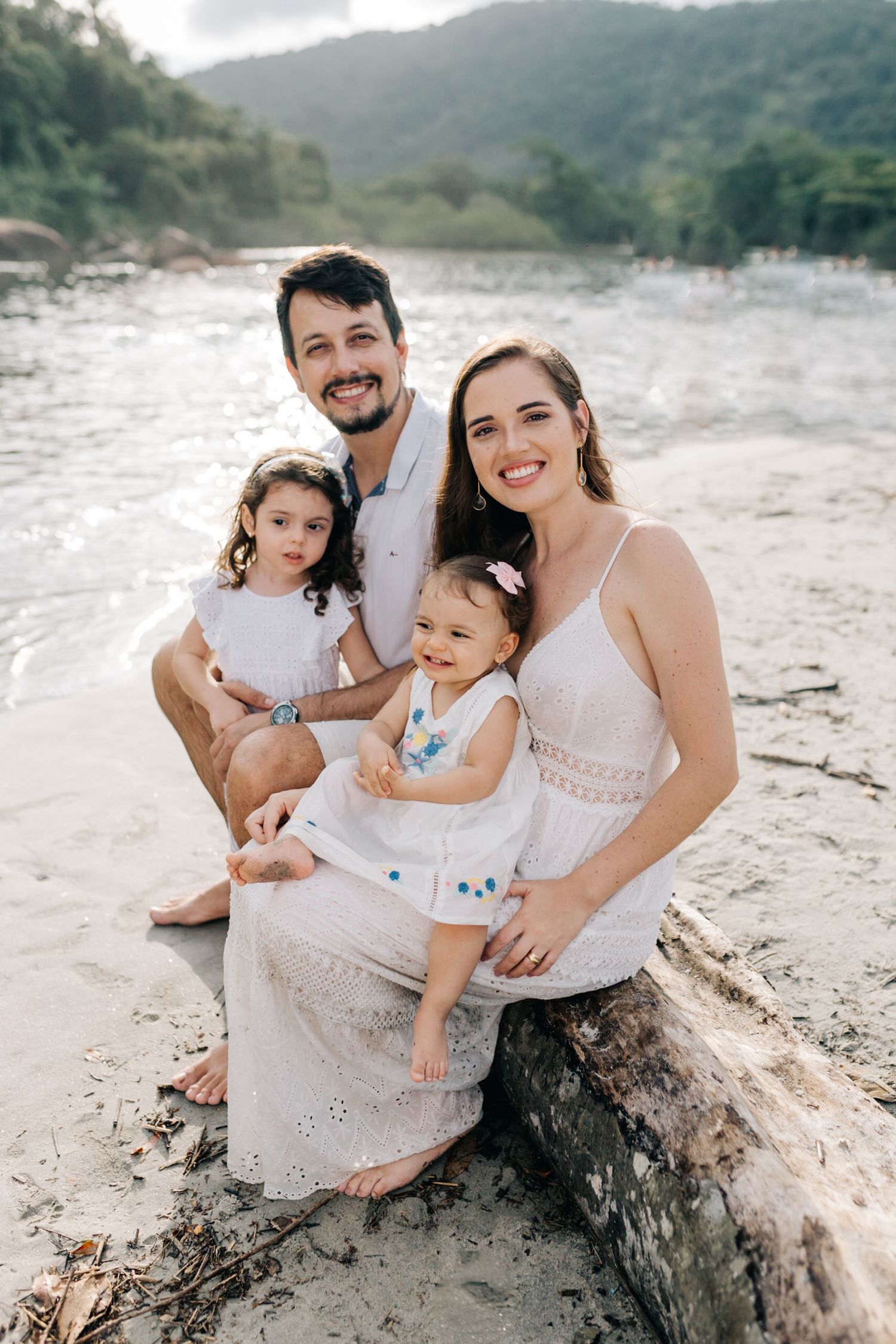 A beautiful family portrait on a beach log with mountains in the background.