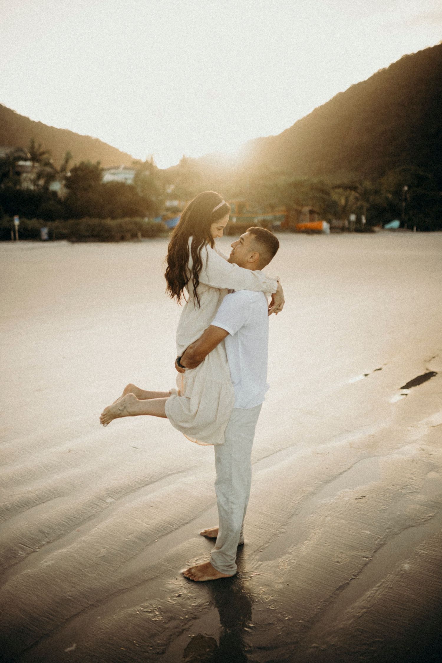Romantic couple shares joyful moment on beach during sunset.