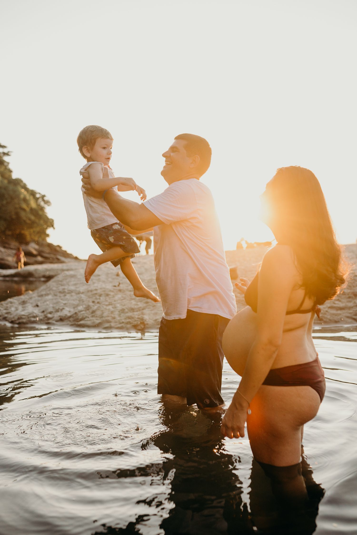 Playful sunset beach photoshoot with family standing in shallow water.