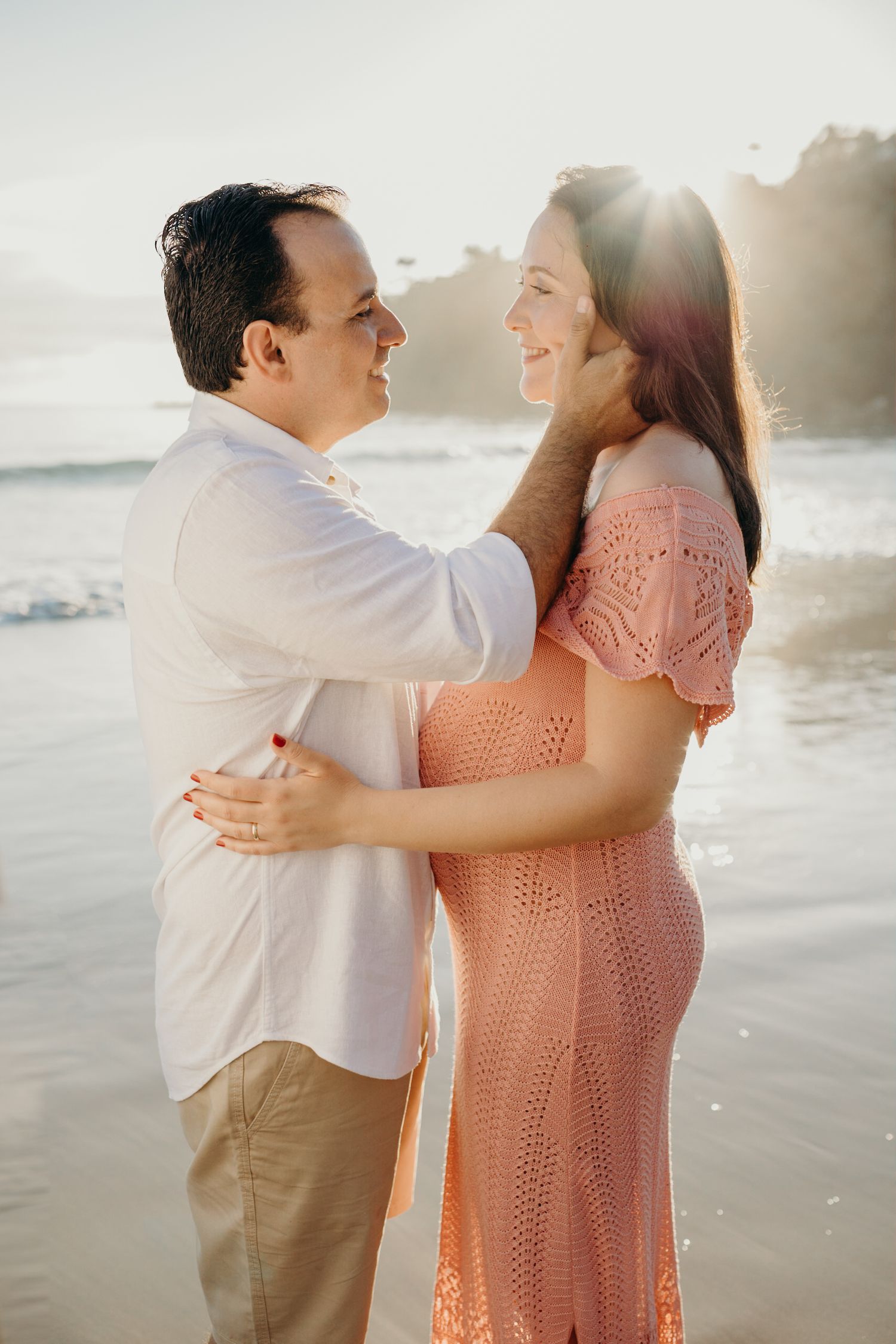 Loving family moment captured in soft sunset lighting at the beach.