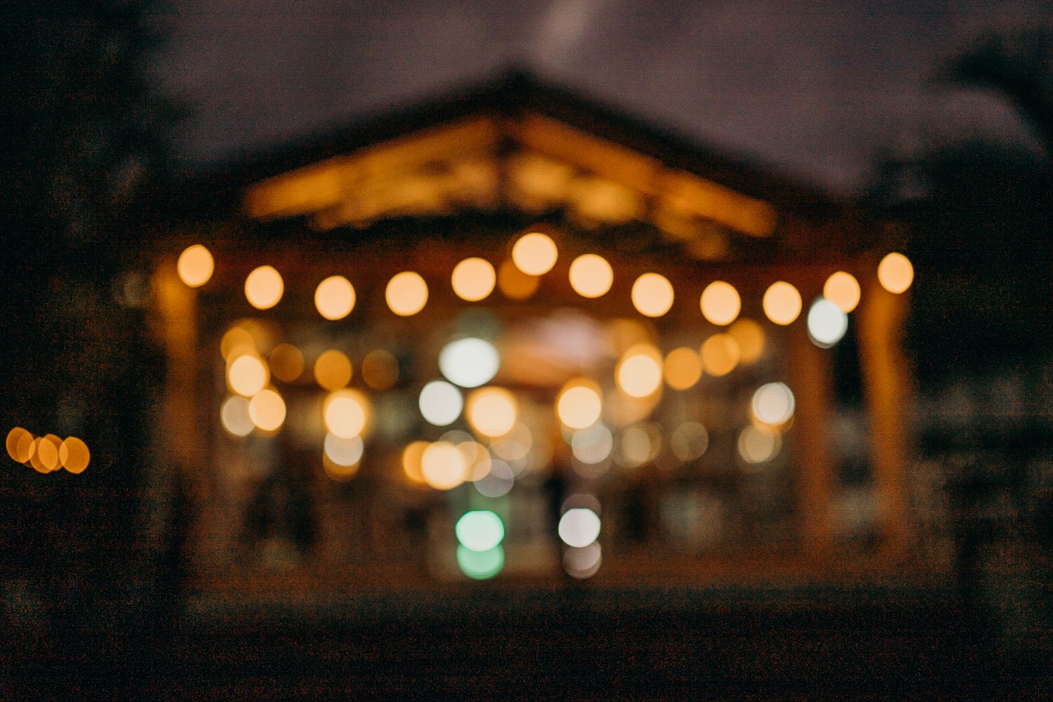 Blurred evening view of pergola with glowing string lights creating bokeh effect.