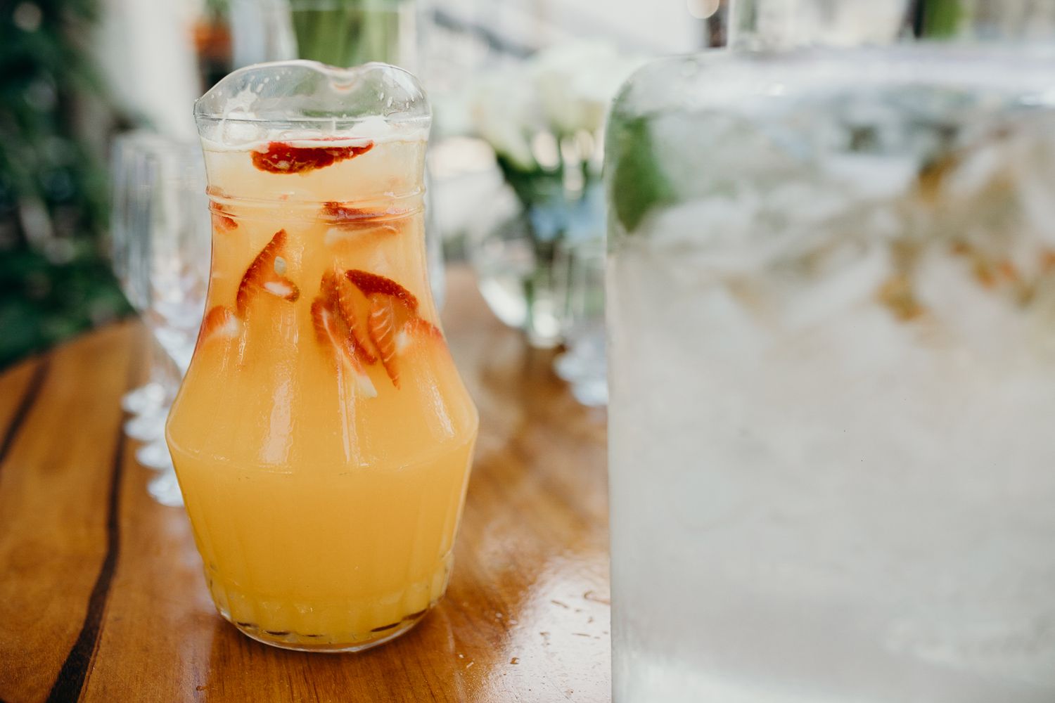 Large glass dispensers of refreshing citrus-infused beverages displayed on wooden surfaces.