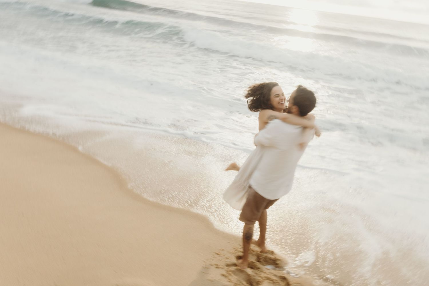 A romantic embrace on the beach with ocean waves in soft focus.