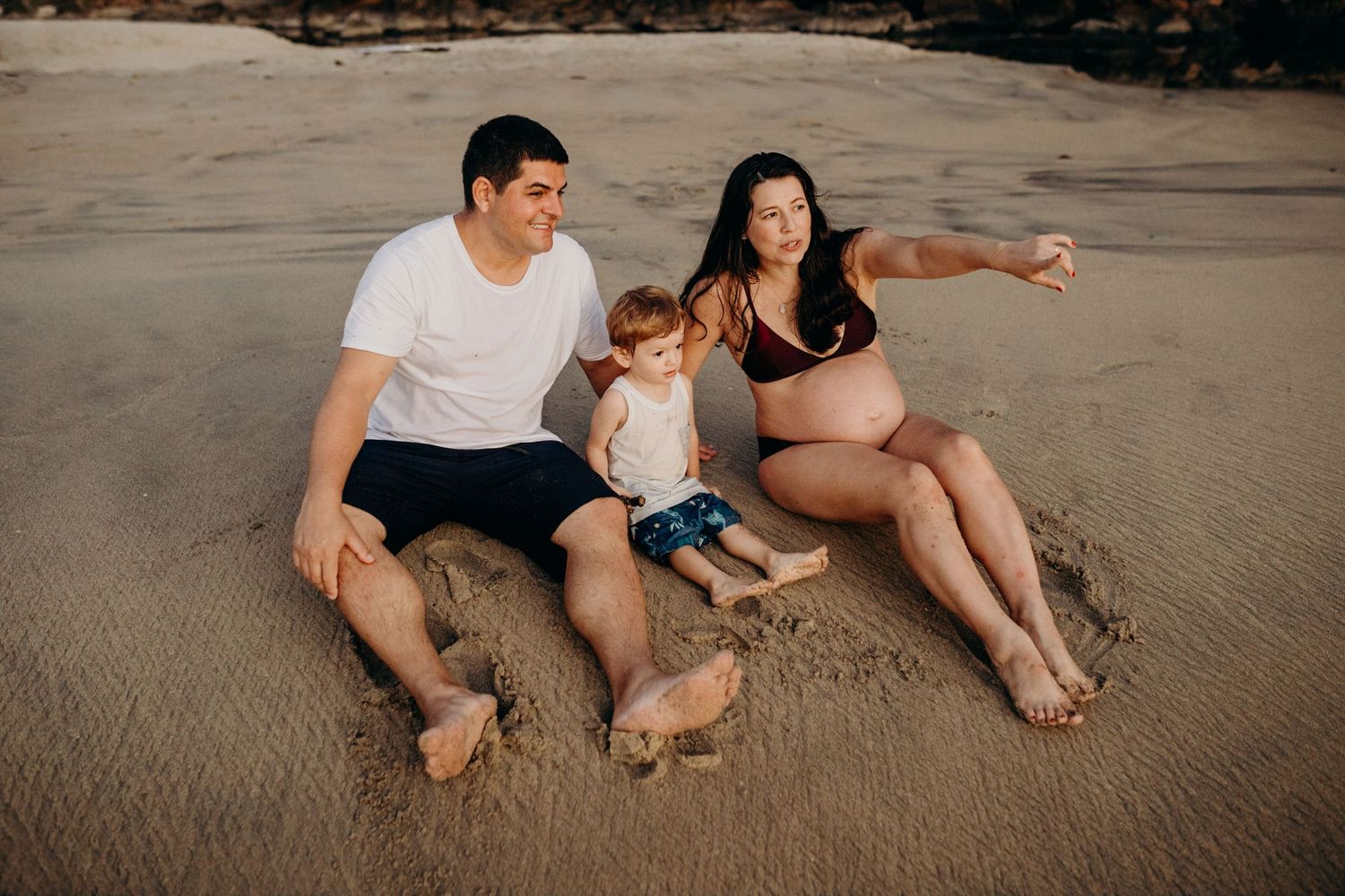 Family relaxing together on a sandy beach during golden hour.