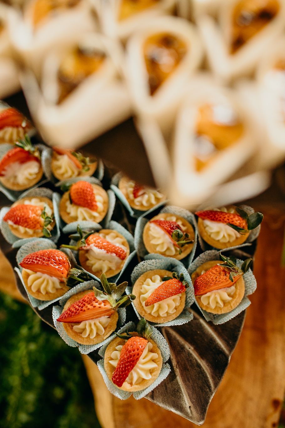Beautifully plated strawberry desserts arranged in rows at a catered event.