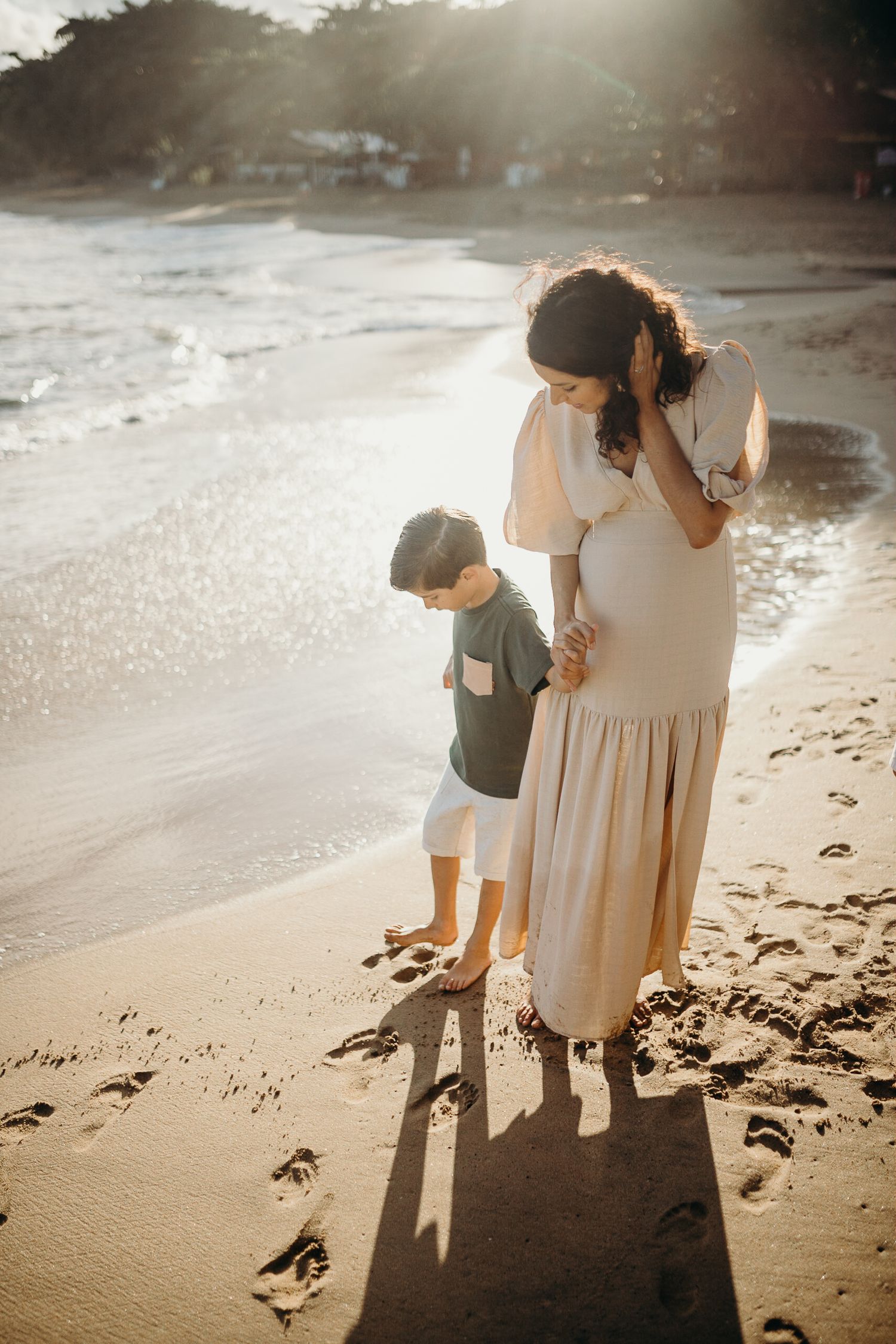 Mother and children exploring beach together in warm evening light.