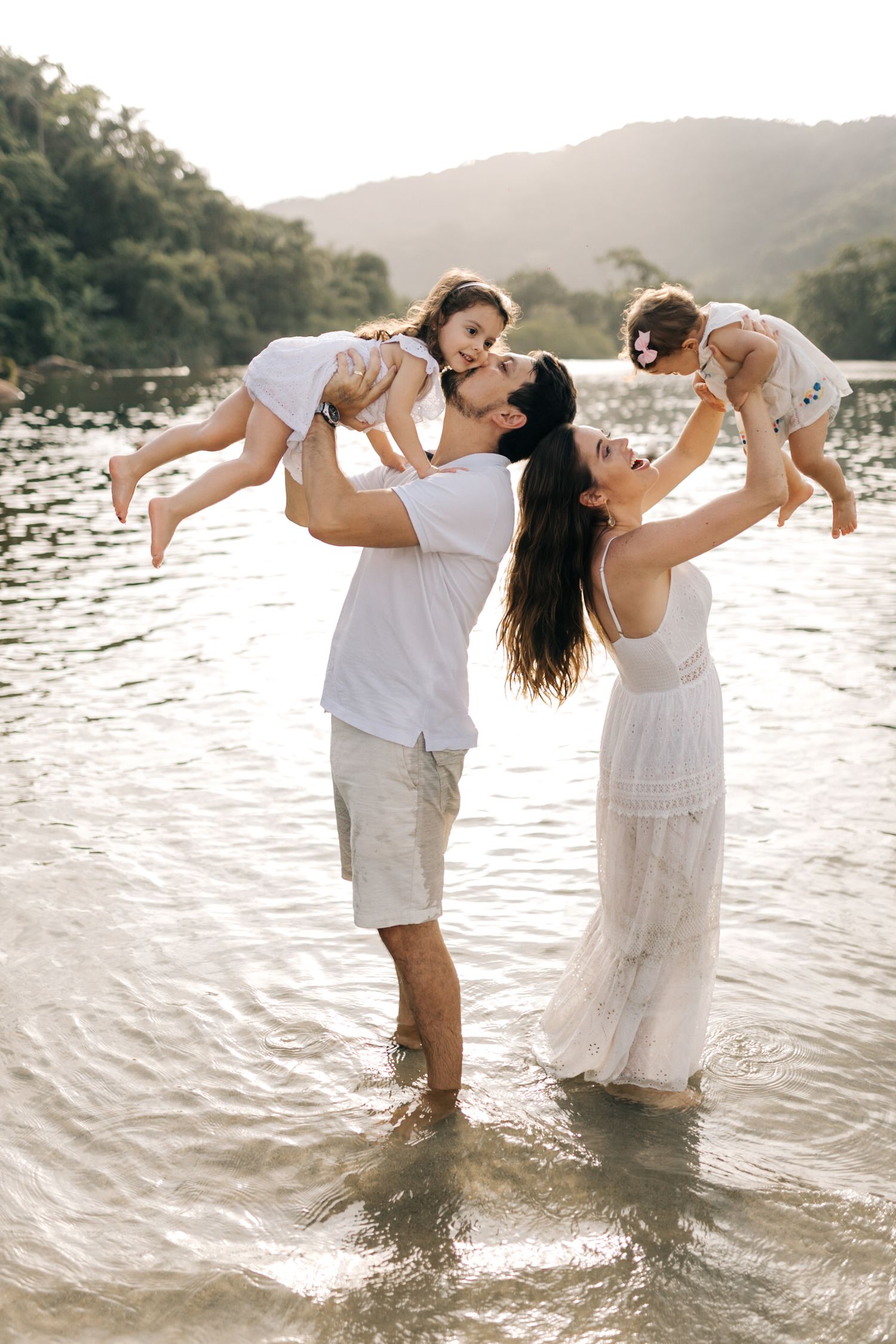 A joyful family plays together in shallow water at sunset by a mountain lake.