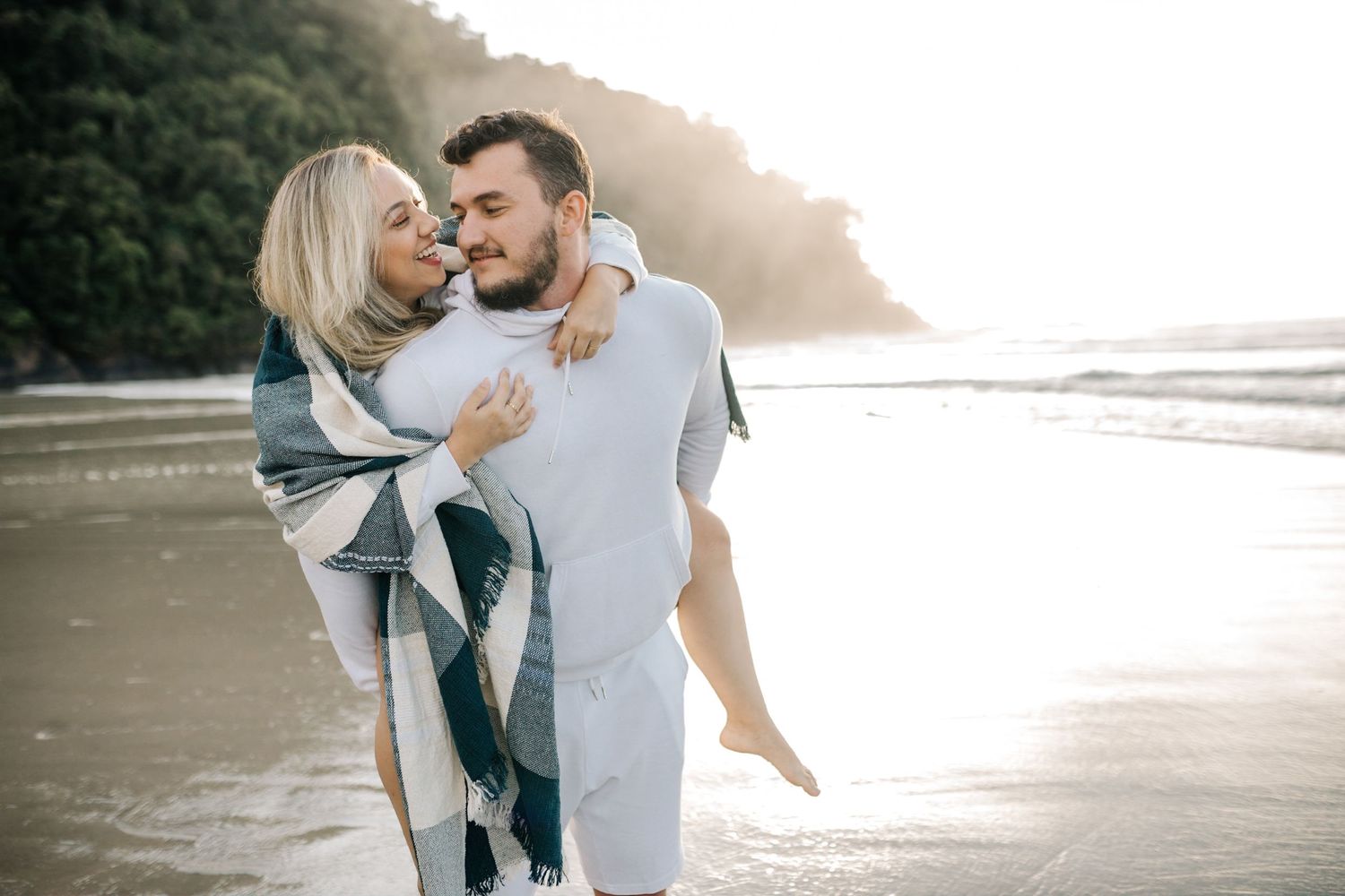 Intimate moment between couple during sunset beach photoshoot.