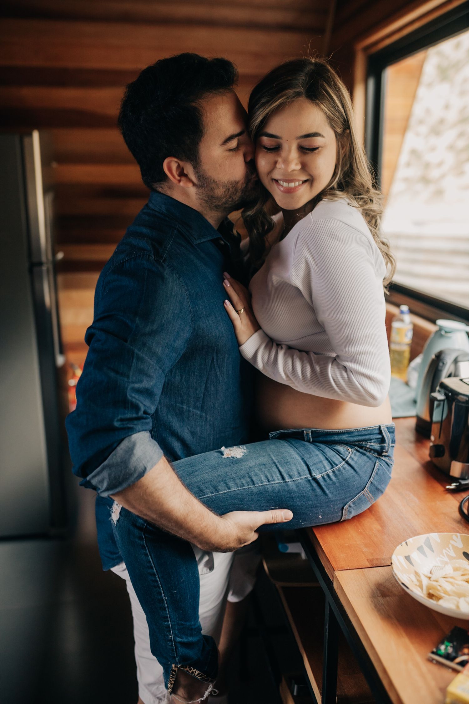 An intimate moment between a couple in a cabin as they share a playful embrace by the window.