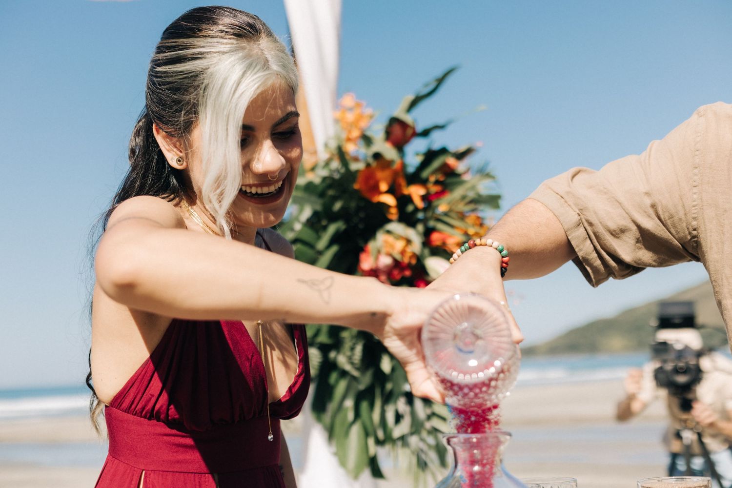 Wedding guests pouring colored sand in a glass container for a unity ceremony tradition.