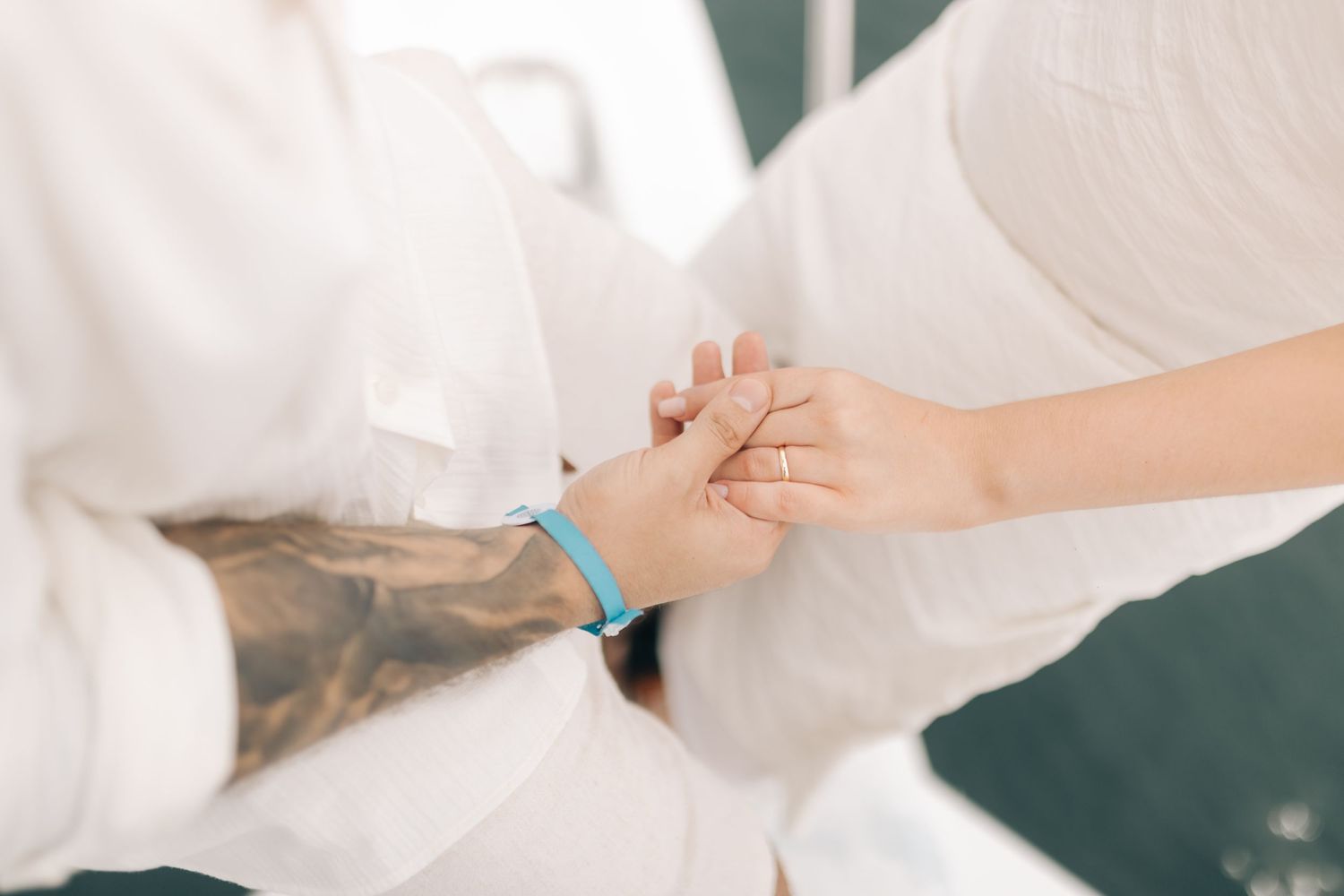 Close-up of hands with turquoise bracelet touching on white boat deck.