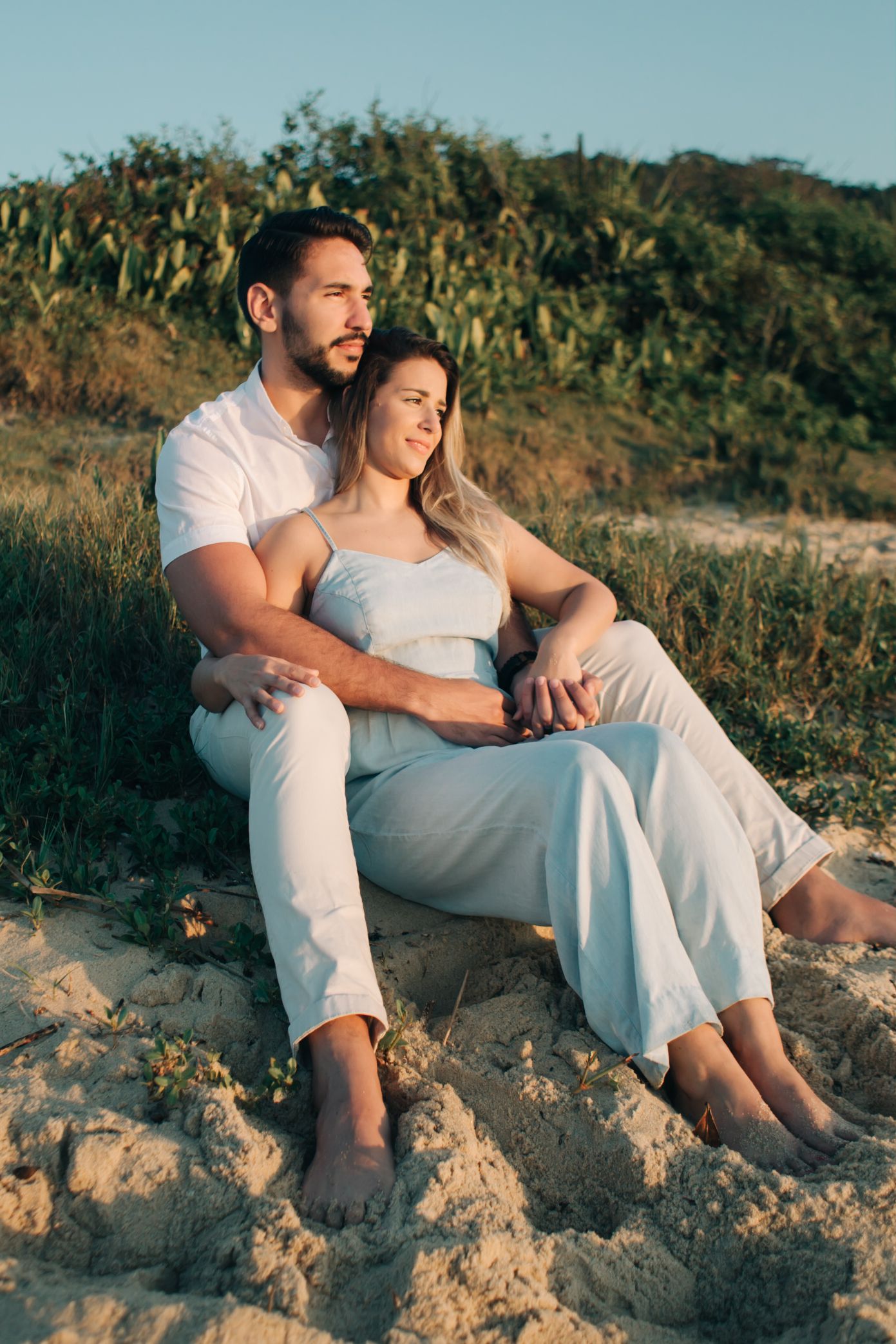 Couple relaxing on sandy beach rocks during a warm sunset evening.