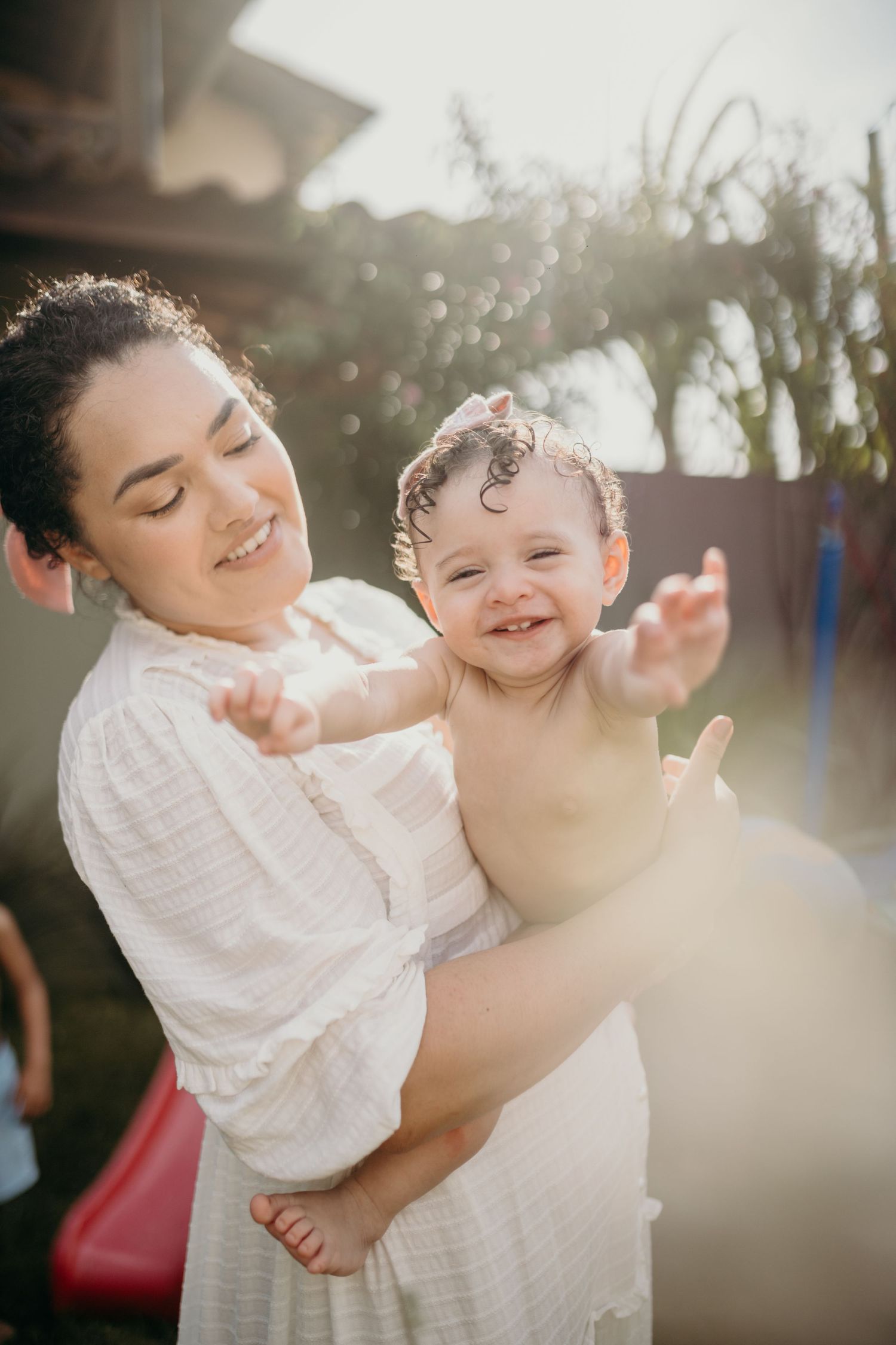 A candid moment of joy between parent and child in sunlit outdoor setting.