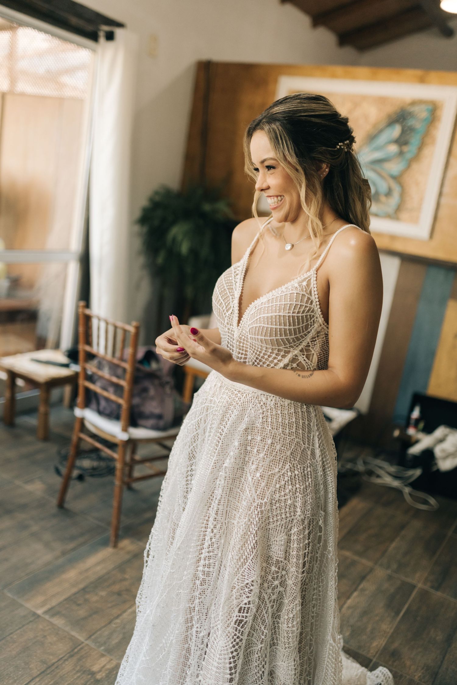 Delicate lace bridal gown with spaghetti straps displayed in natural indoor lighting.