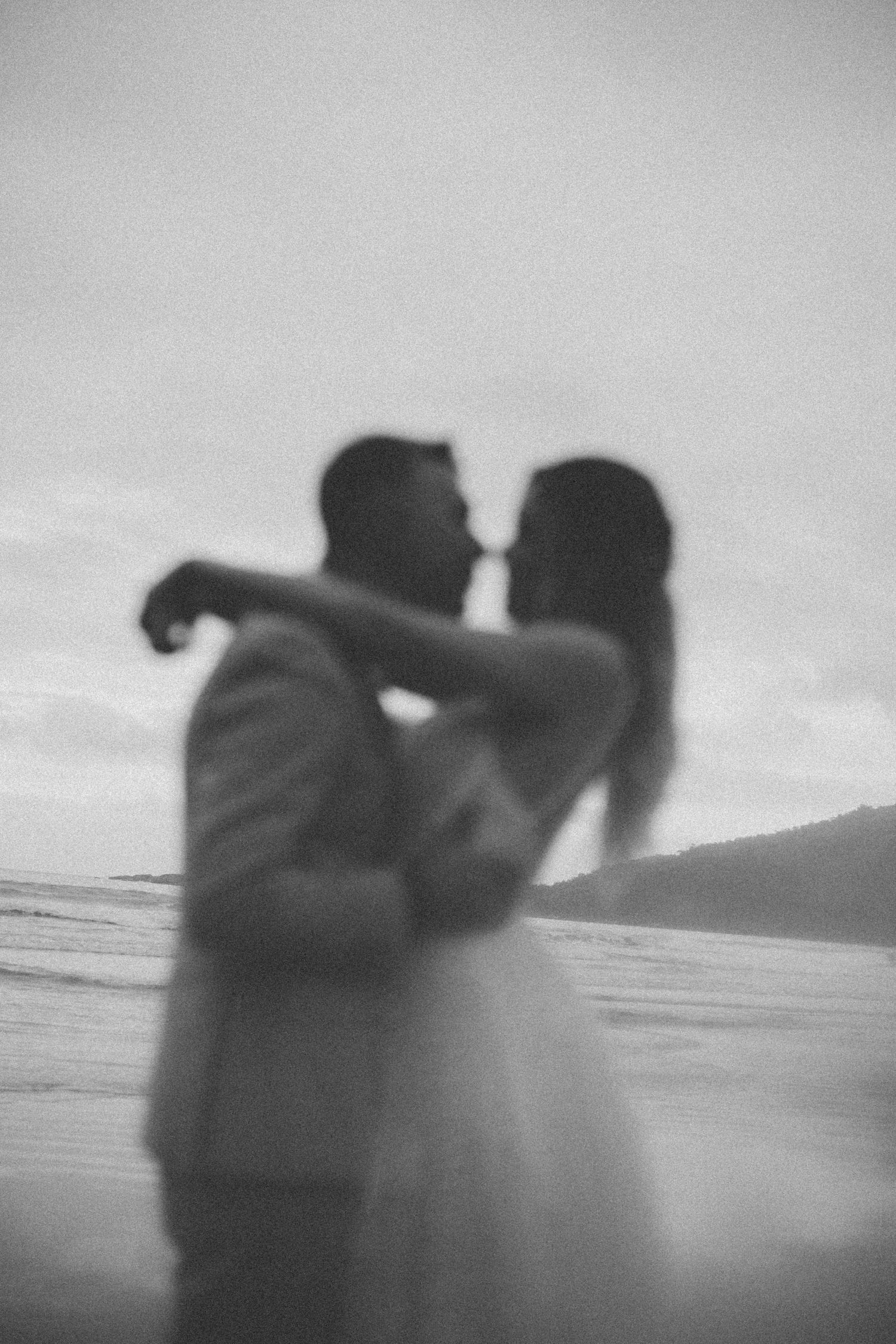 A dreamy black and white silhouette of a couple dancing on the beach.