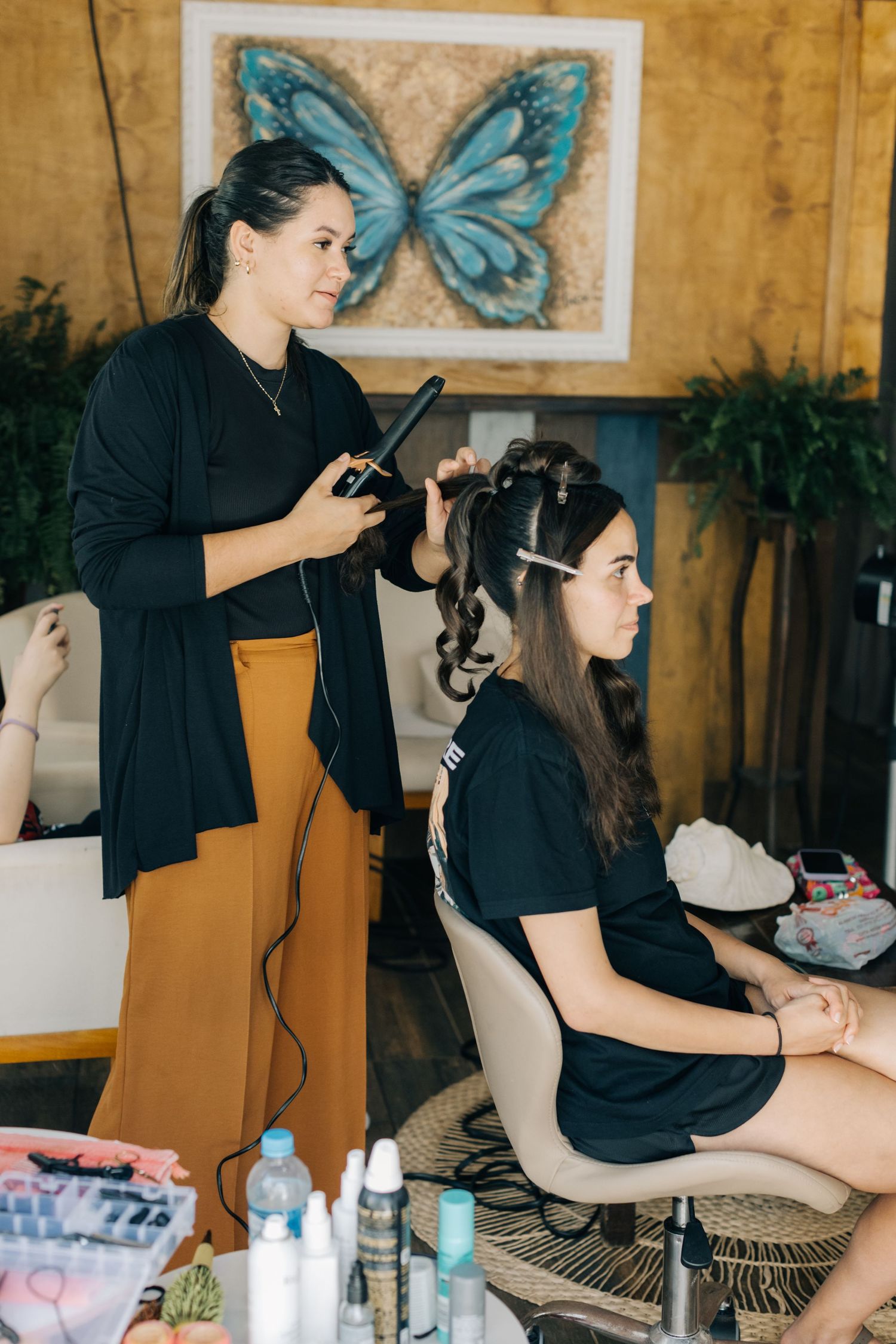 Beauty professionals work on hair styling in a salon with butterfly decor.