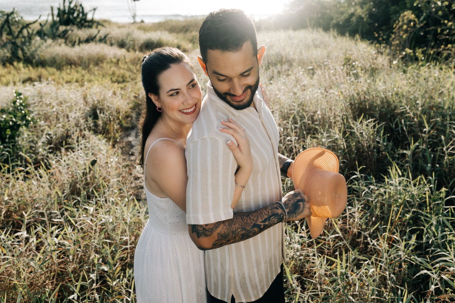 Couple sharing playful moments in scenic outdoor setting during golden hour.
