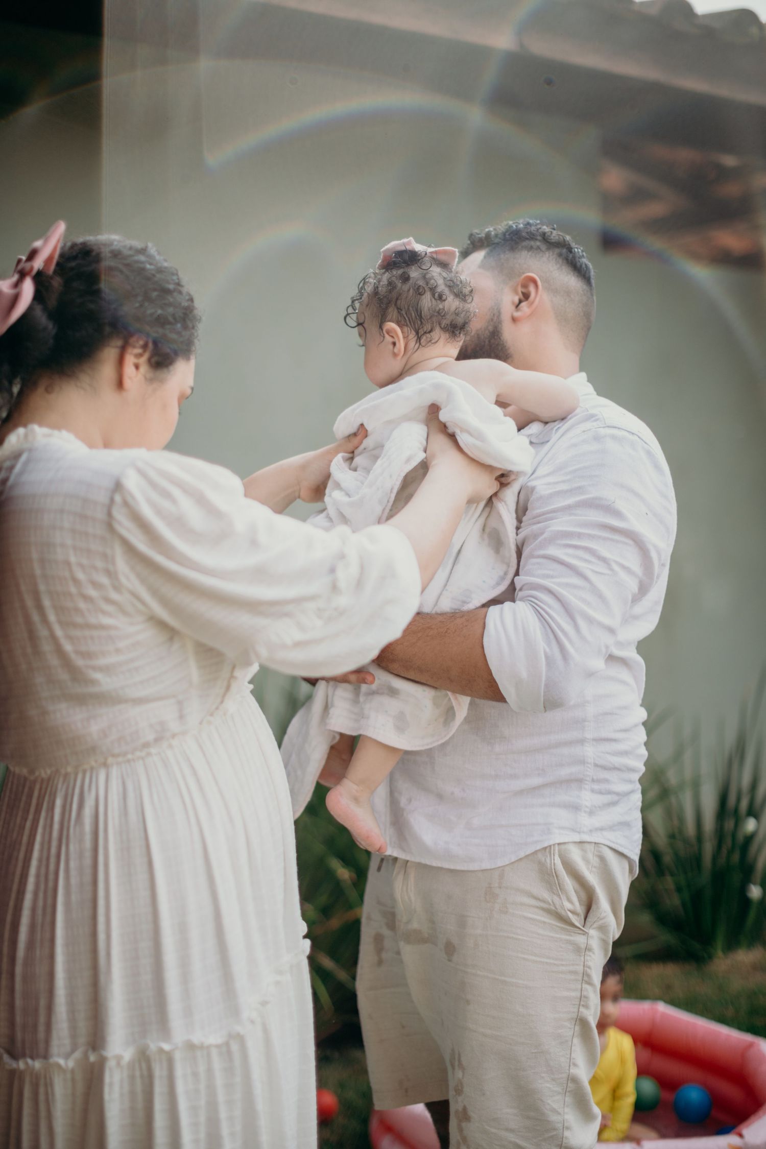 A tender dance moment in white clothing against a soft grey background.