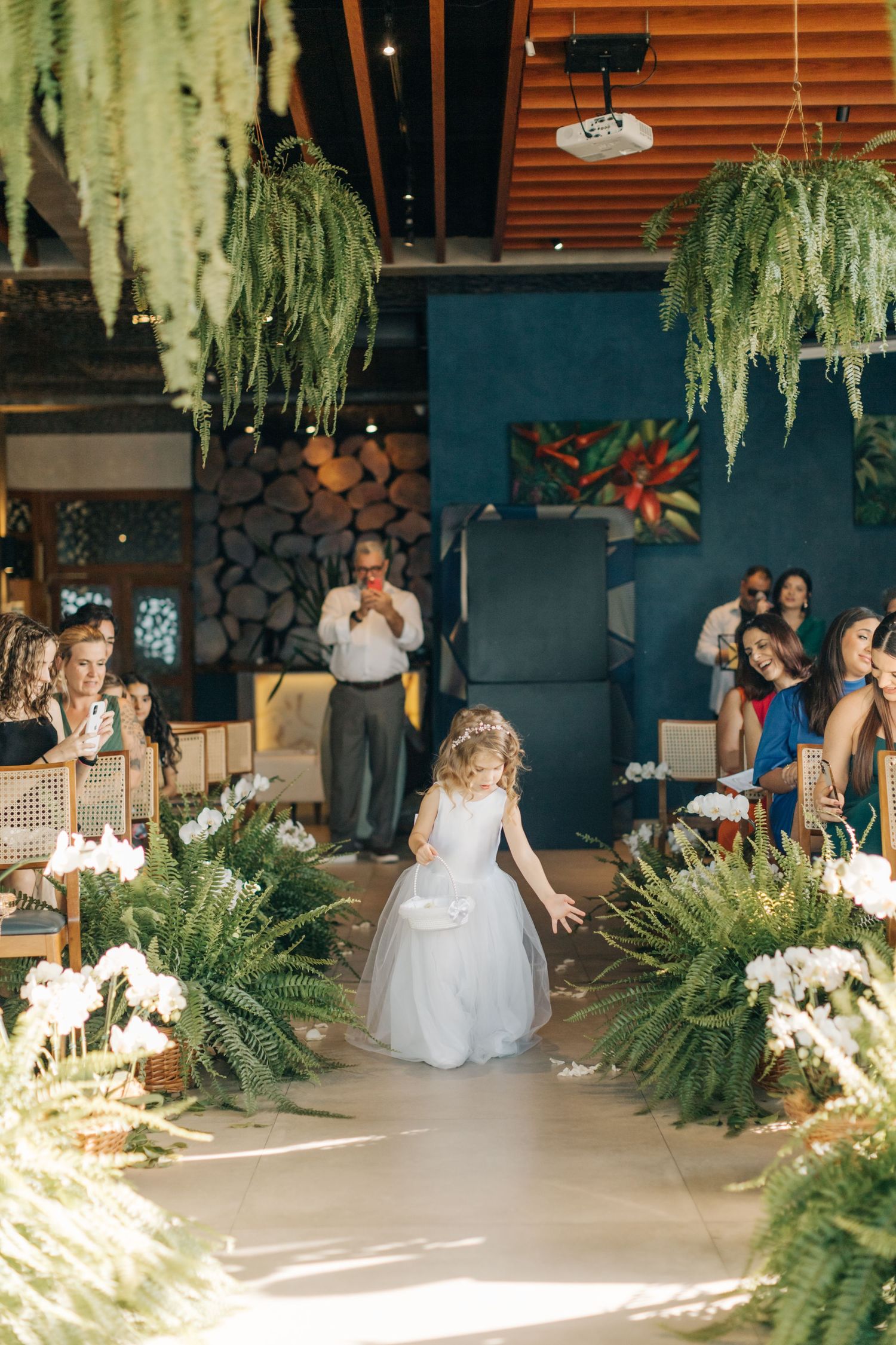 Wedding venue decorated with hanging greenery and white floral arrangements along an aisle.