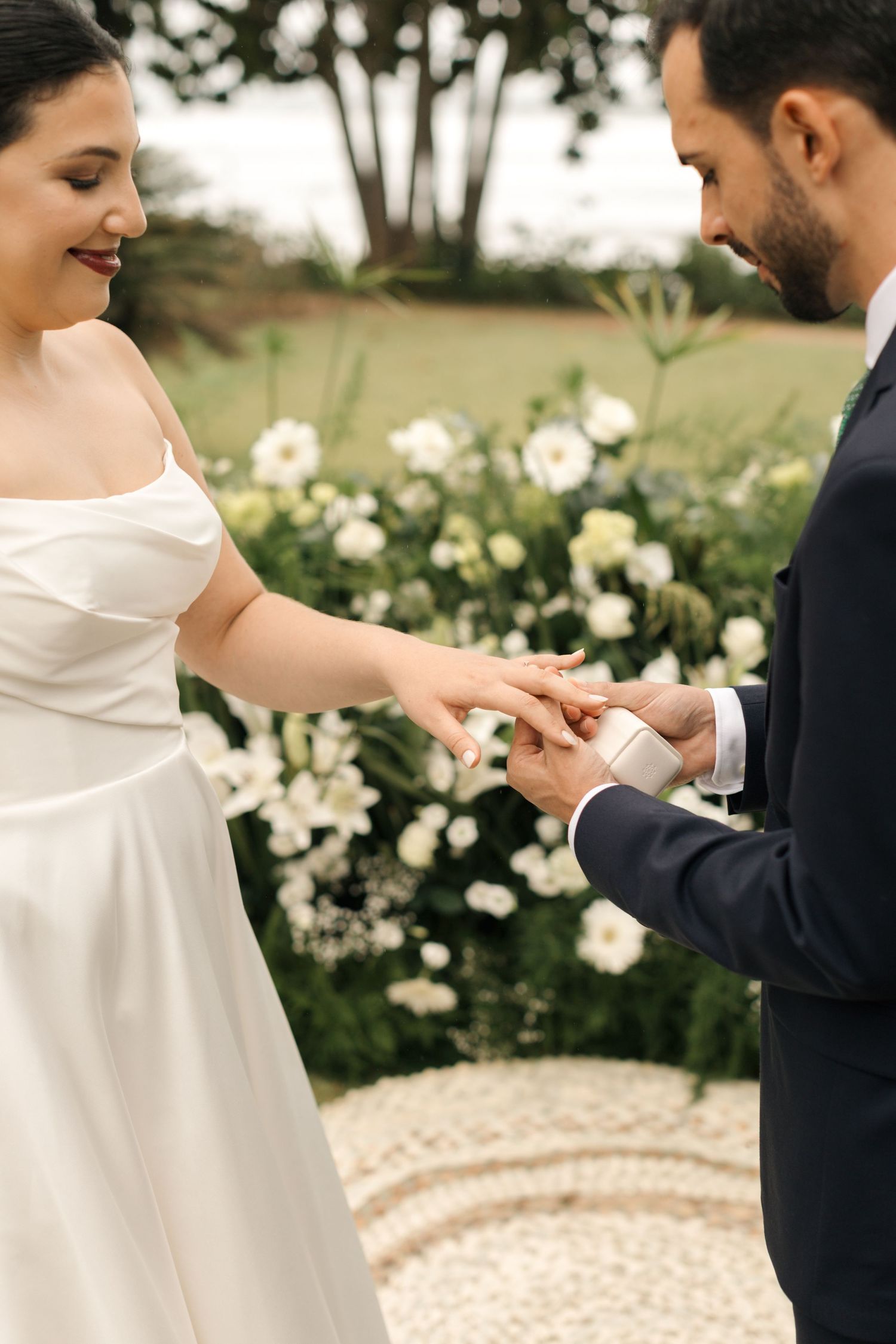 Wedding ceremony moment captured among white roses in garden setting.