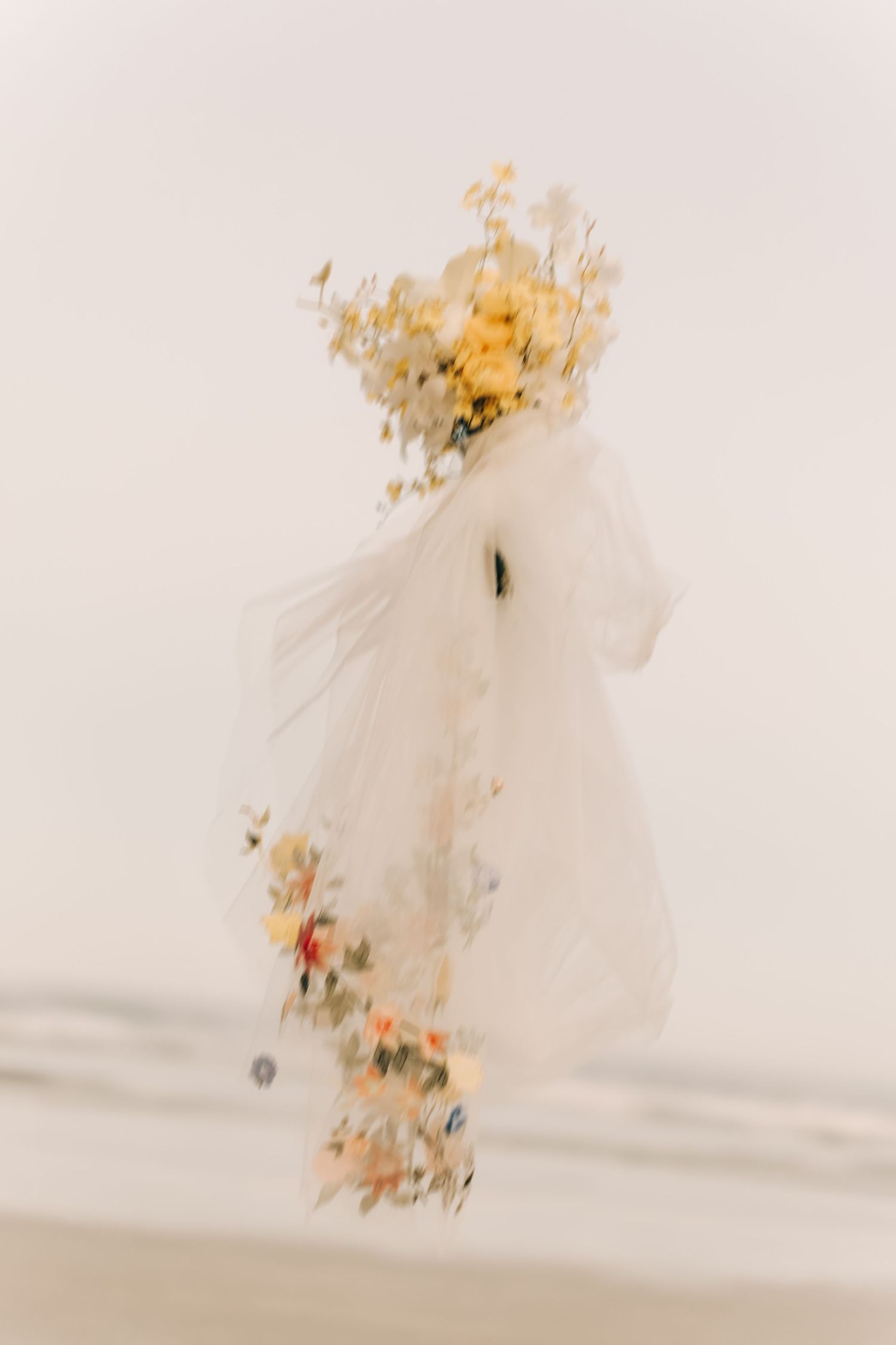 Abstract motion blur of a wedding dress and yellow flowers against a light background.