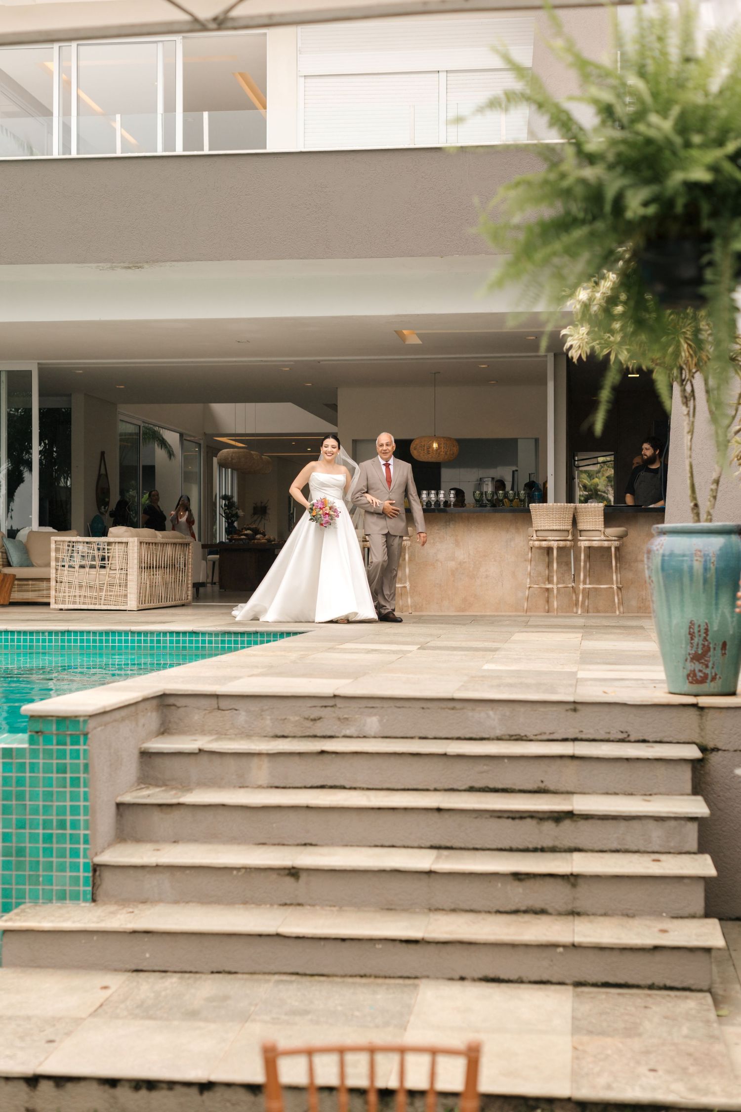 Modern venue exterior with concrete steps and turquoise tile accents near a swimming pool.