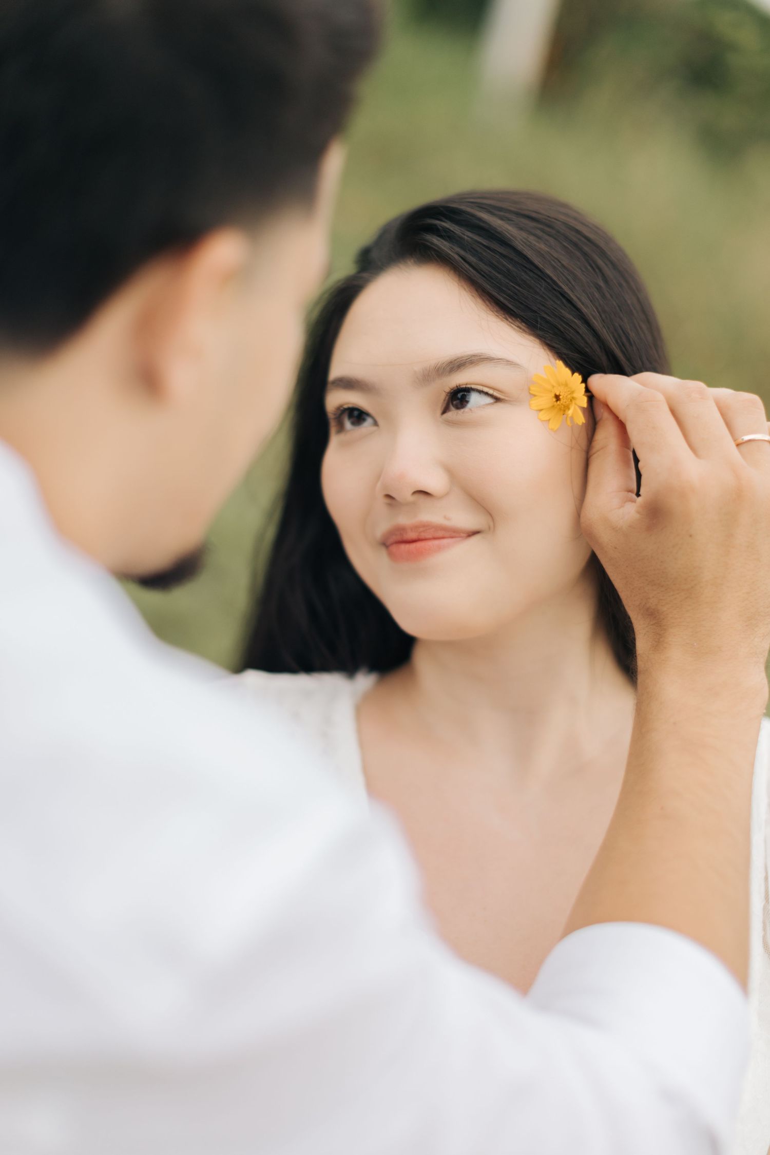 Sweet moment as yellow flower is placed in hair during outdoor photoshoot.