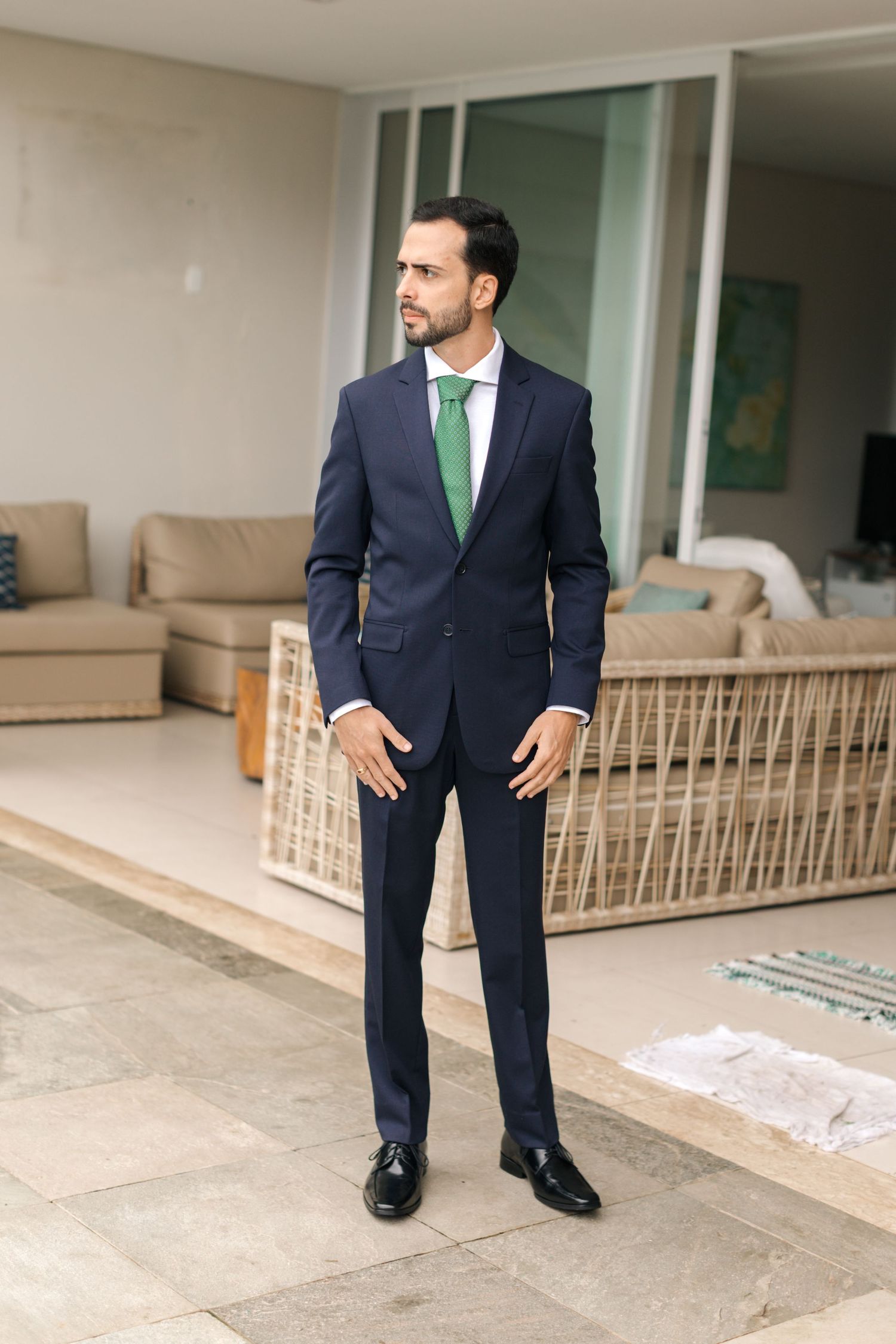 Professional in navy suit with emerald tie stands on outdoor patio.