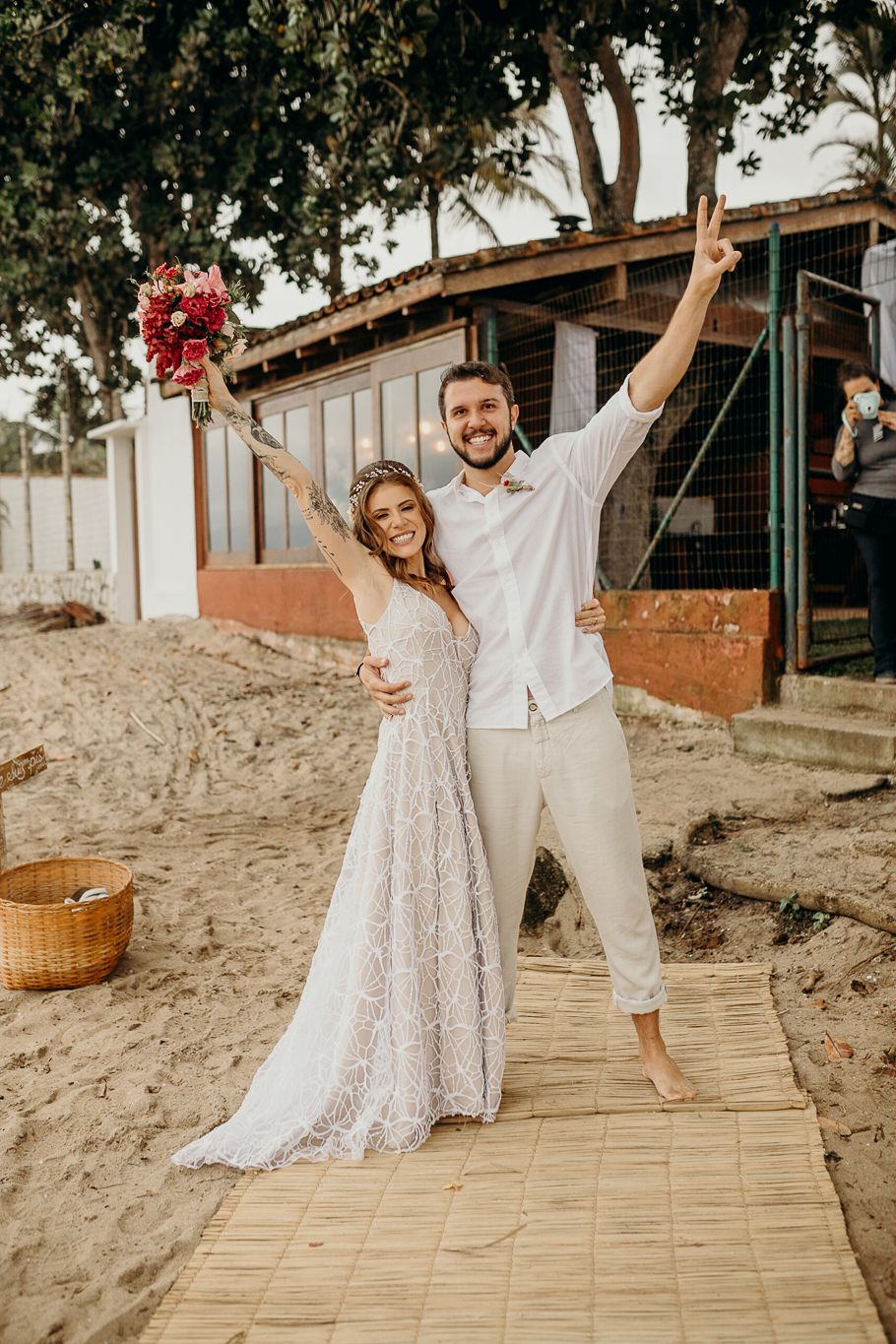 A celebratory pose on a beach boardwalk during a tropical wedding.